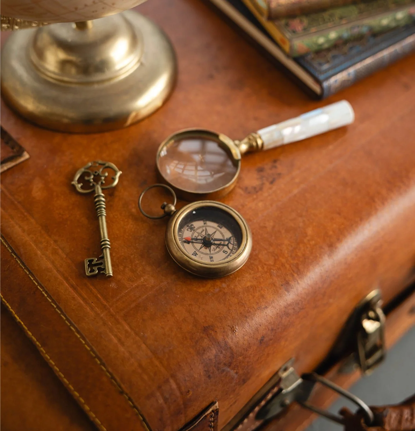 Brújula, llave y lupa sobre una maleta: símbolos de autoconocimiento y exploración del mundo interior.