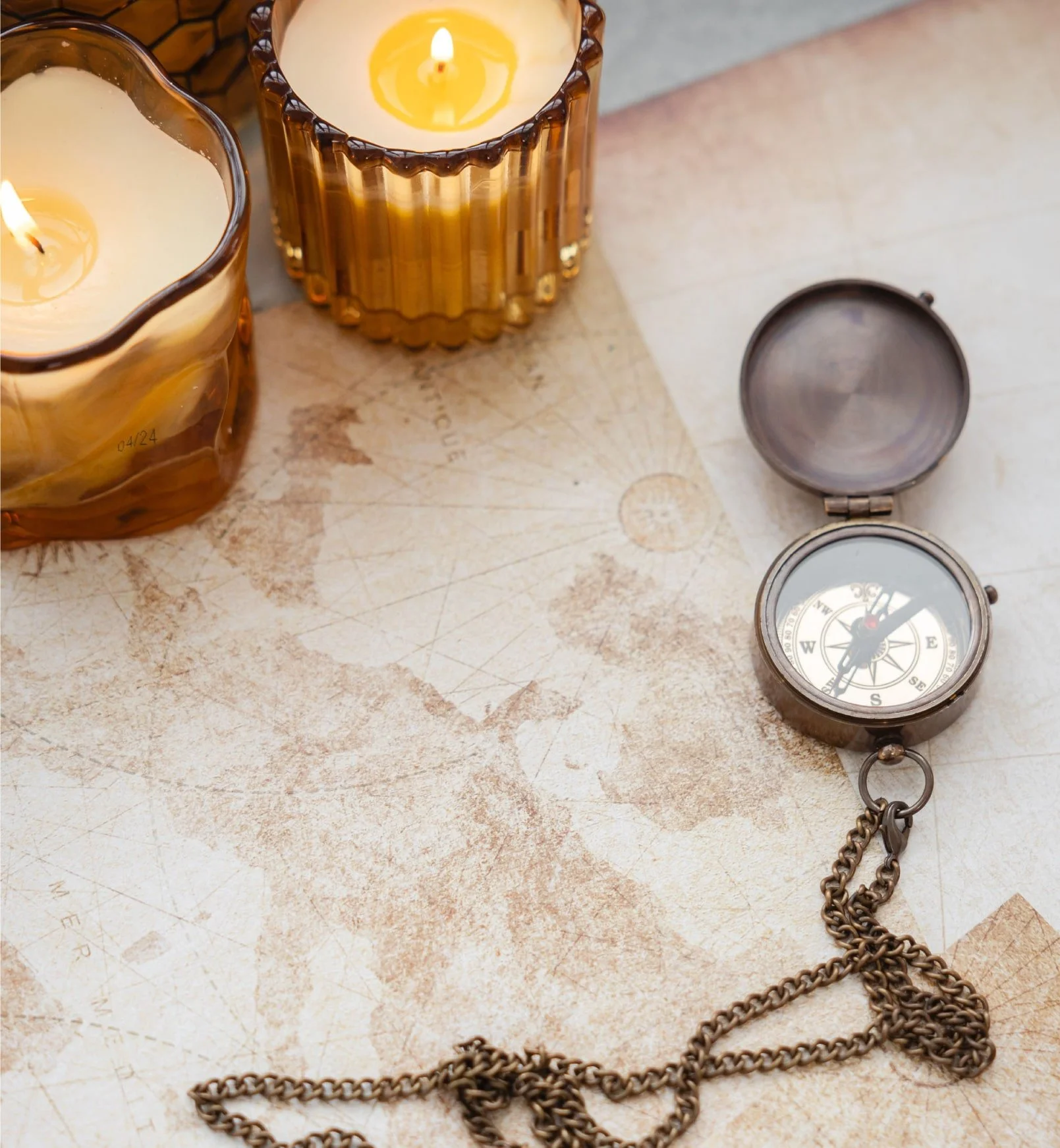 Brújula antigua sobre un mapa con velas encendidas, simbolizando la luz interna, el viaje de autoconocimiento y la búsqueda de dirección interior.