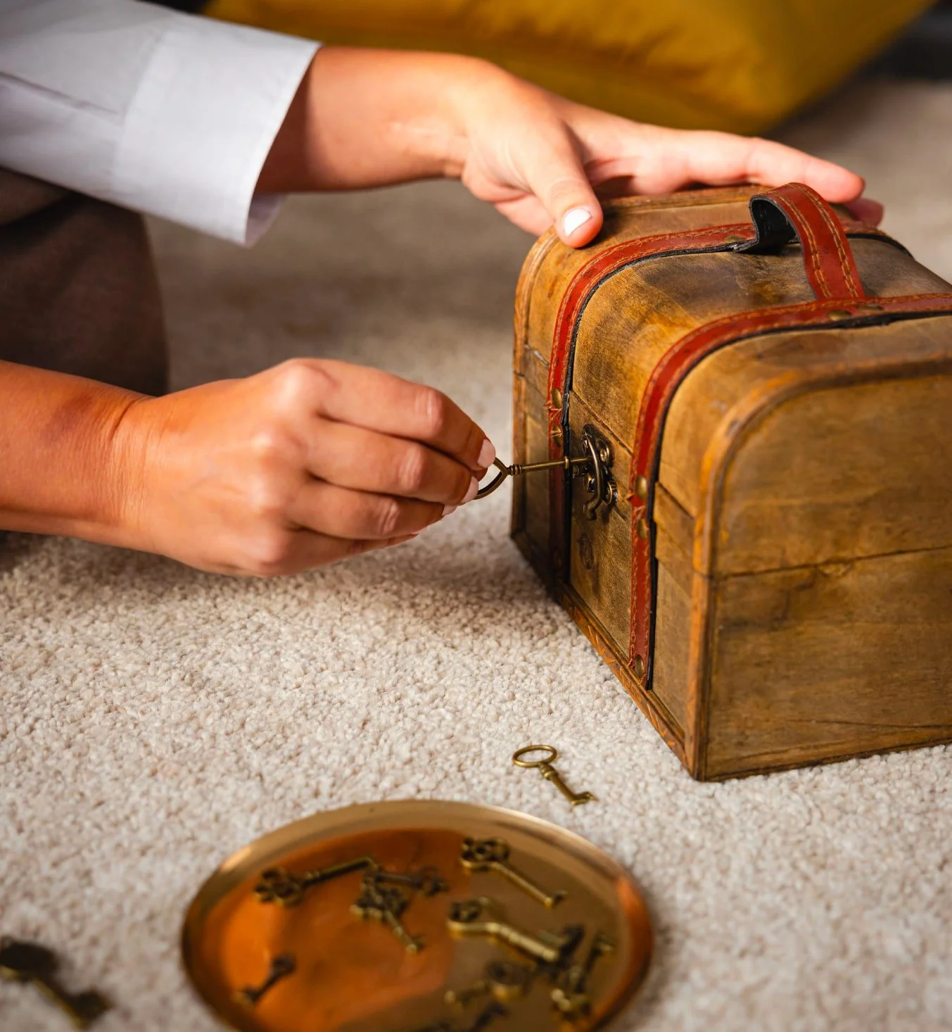 Manos abriendo un pequeño cofre de madera con una llave antigua, rodeado de otras llaves, representando el desbloqueo de memorias inconscientes y el acceso al poder interior.