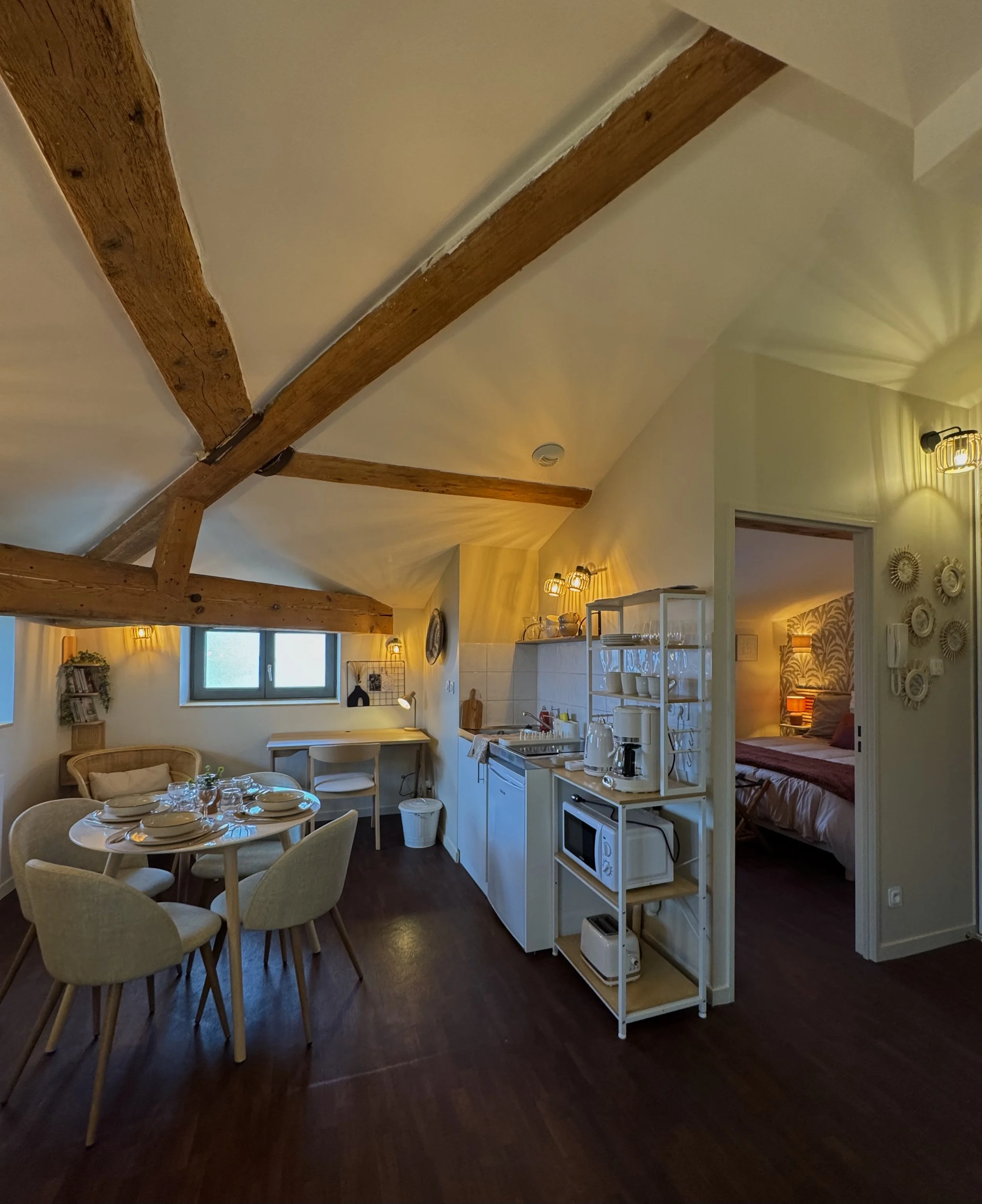 Salon lumineux de la Suite Cocon à Lyon 5, entre poutres apparentes et décoration terracotta, idéal pour se détendre après une journée à Fourvière.