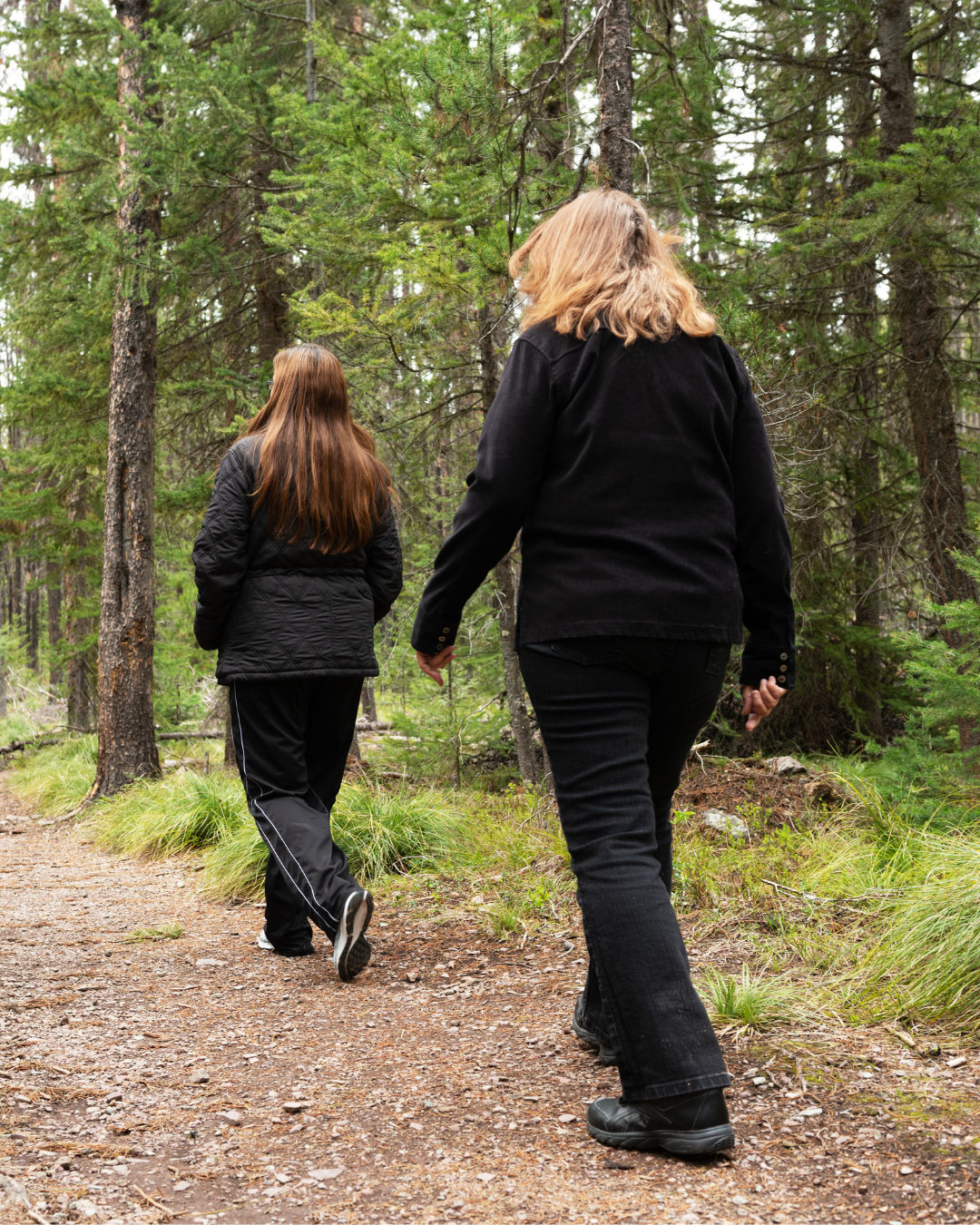 Twee vrouwen wandelen samen over een bospaadje – energie en balans opbouwen.
