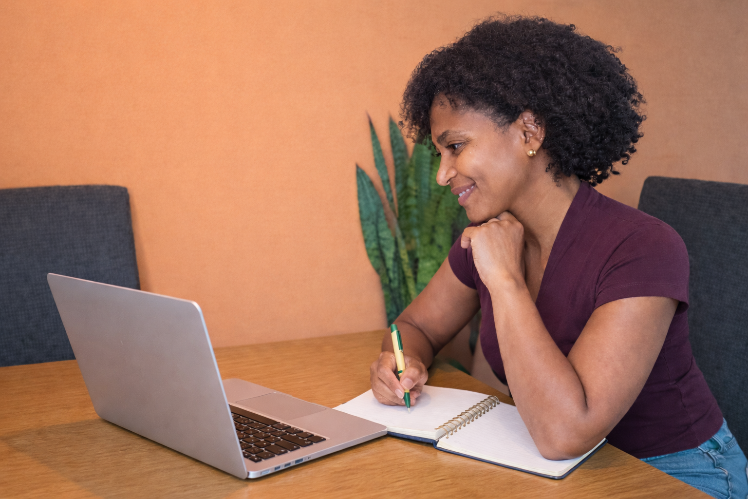 Fátima, leefstijlcoach, werkt online met laptop en notitieboek tijdens een coachingssessie.