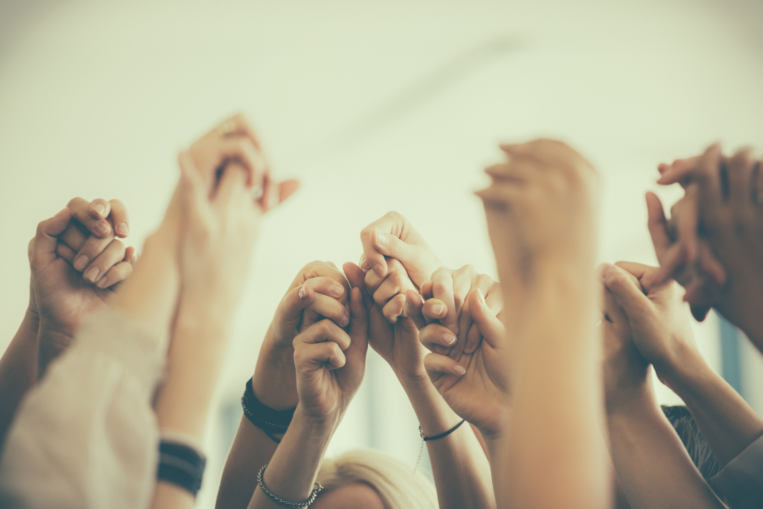 Groep mensen met omhooggestoken handen; samen steun, motivatie en betrokkenheid in de community