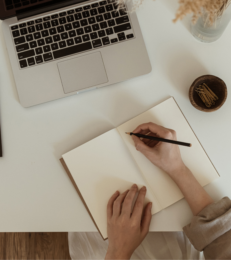 Laptop en notitieboek op bureau, symbool voor online leefstijlcoaching en opdrachten.