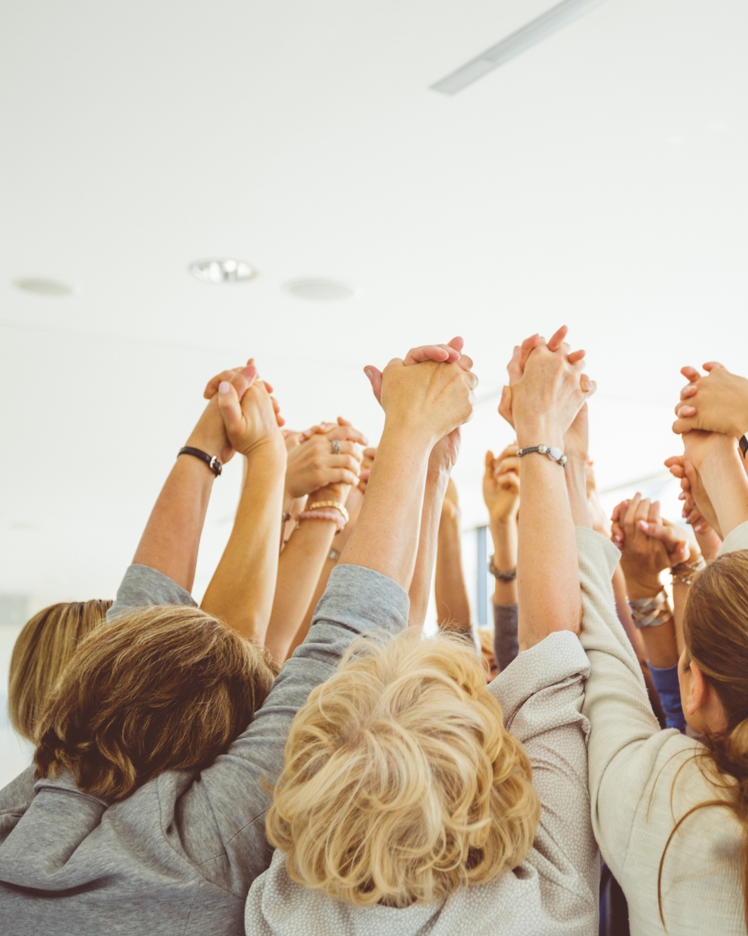 Vrouwen steken samen hun handen omhoog; kleine groep voor steun, motivatie en samen leren.
