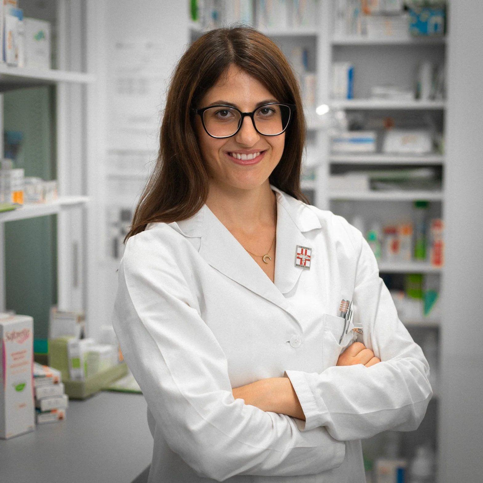 Farmacista donna con occhiali e camice bianco in farmacia