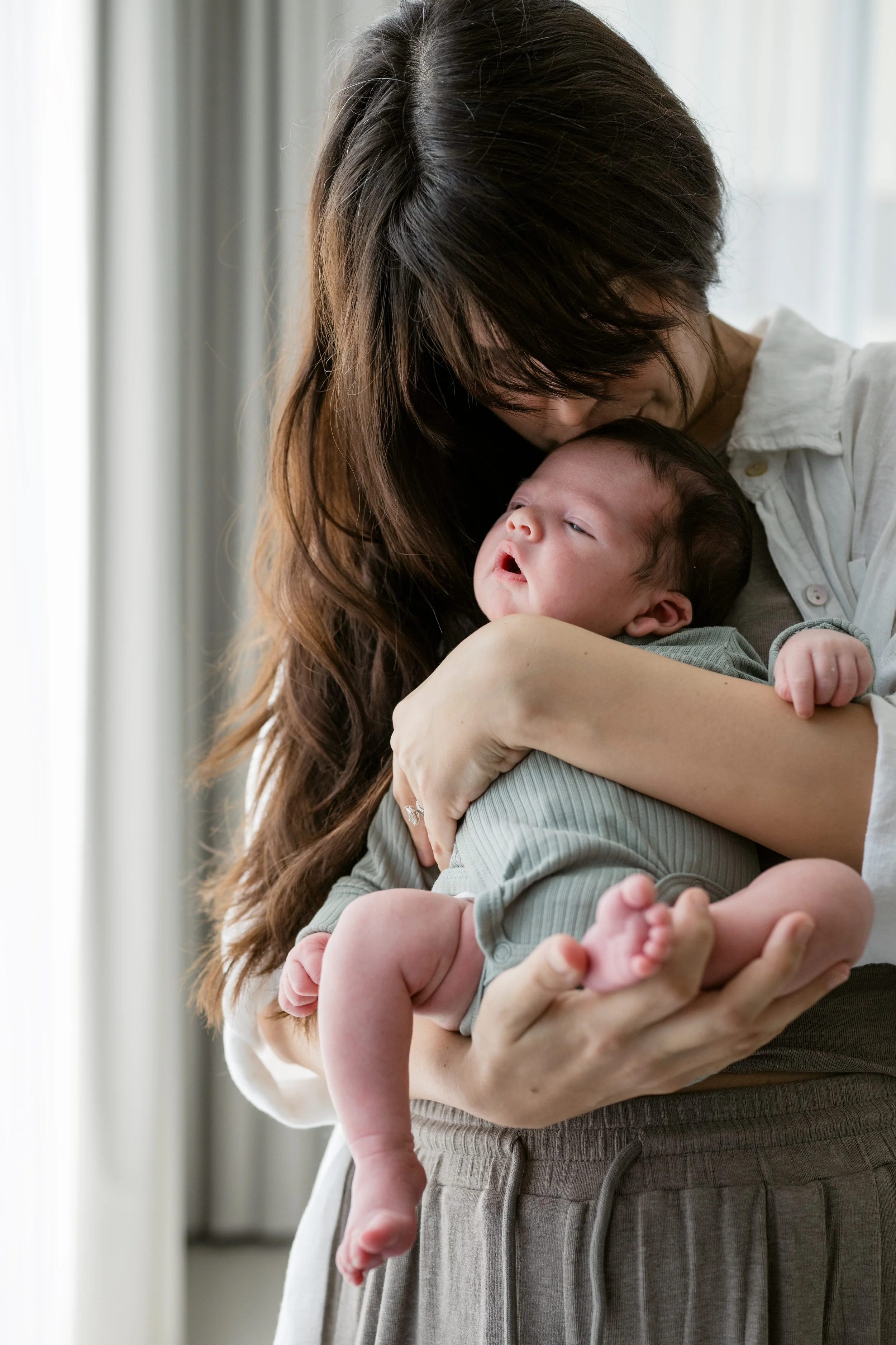 Mother cuddling her newborn baby during a relaxed newborn home session in Dubai