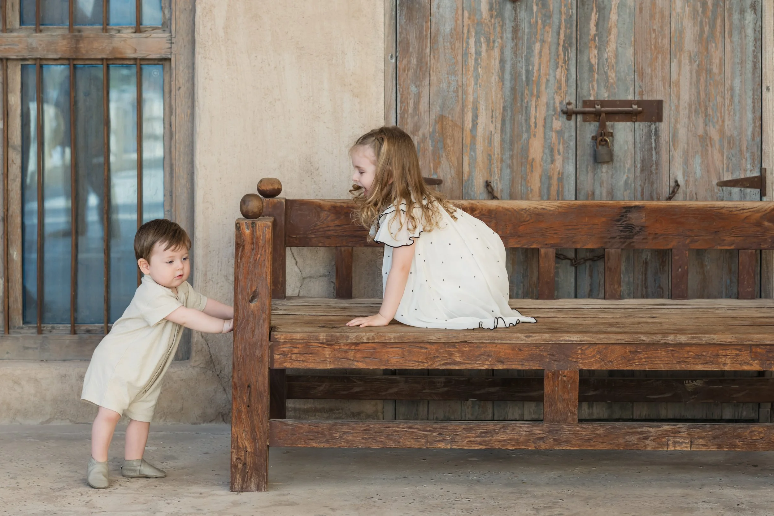 Toddler playing near wooden bench during a candid Dubai family photo session