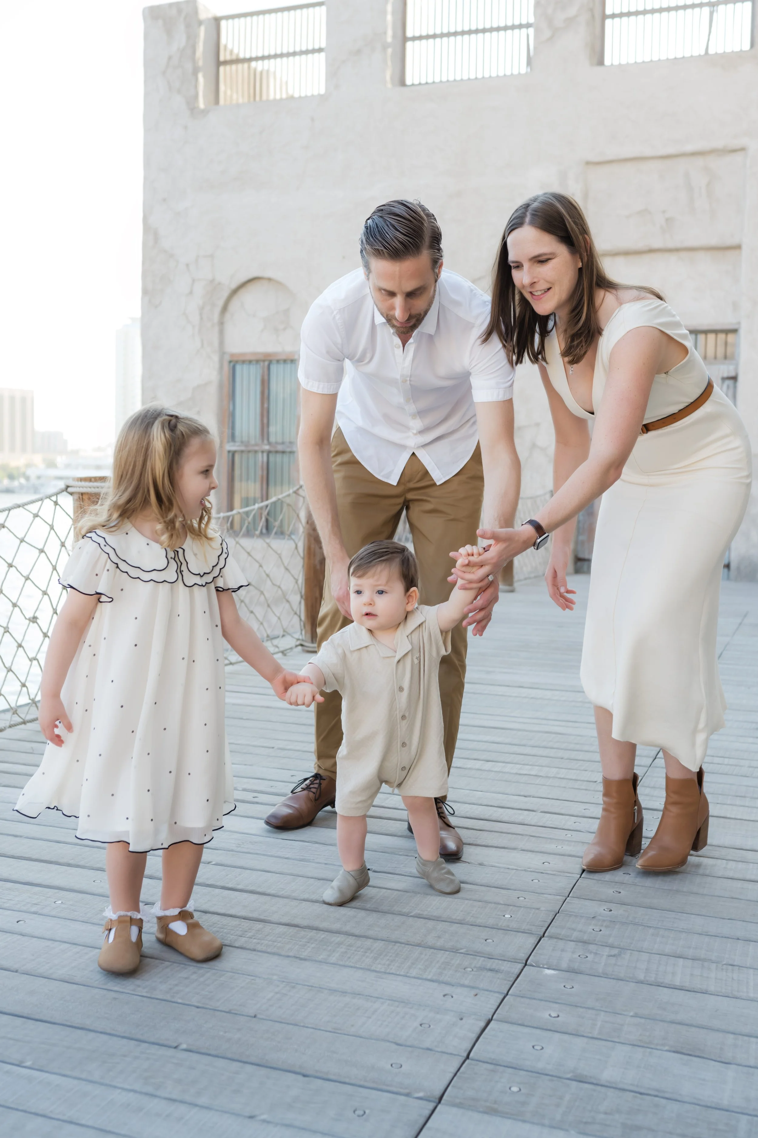 Family helping baby take first steps during an outdoor family photoshoot in Dubai
