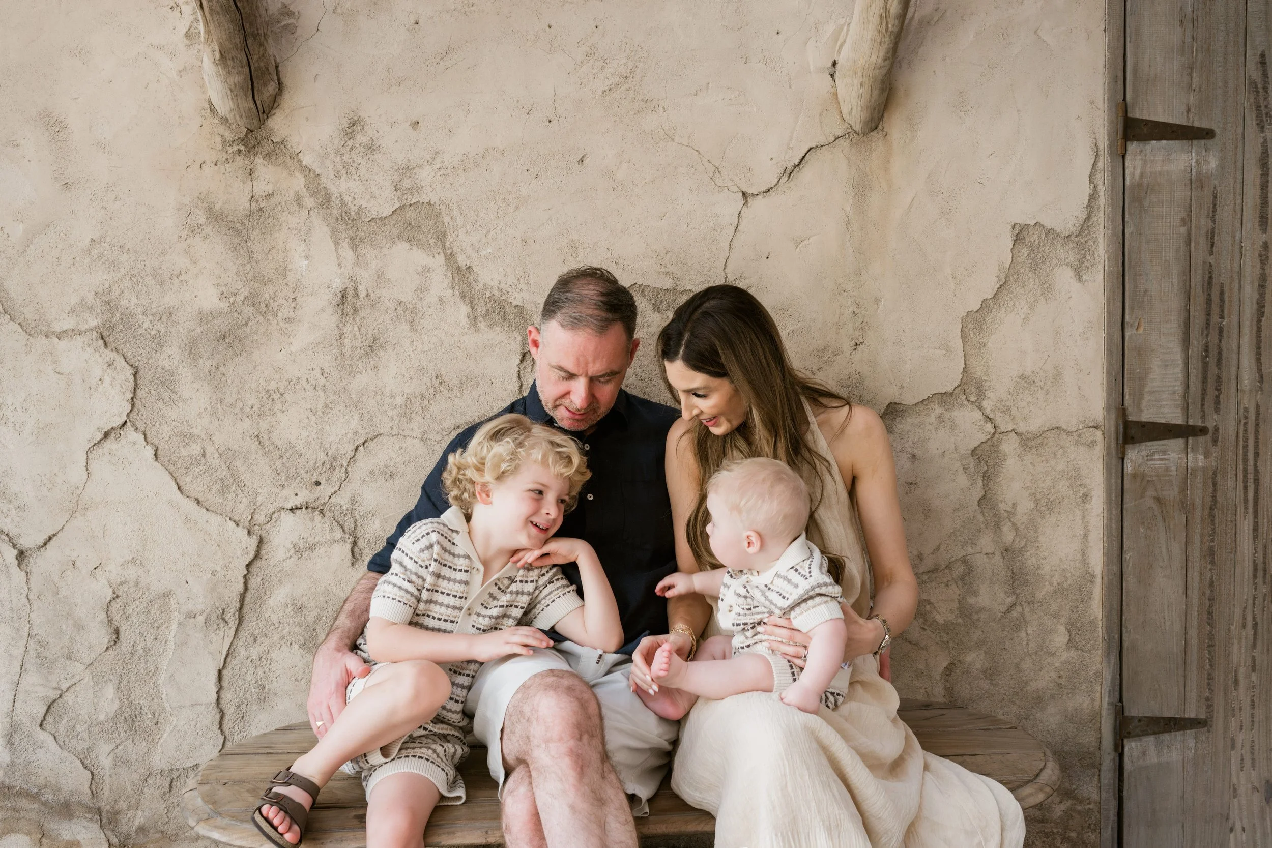 Family of four sitting together on a wooden bench in Old Dubai during a relaxed family photo session