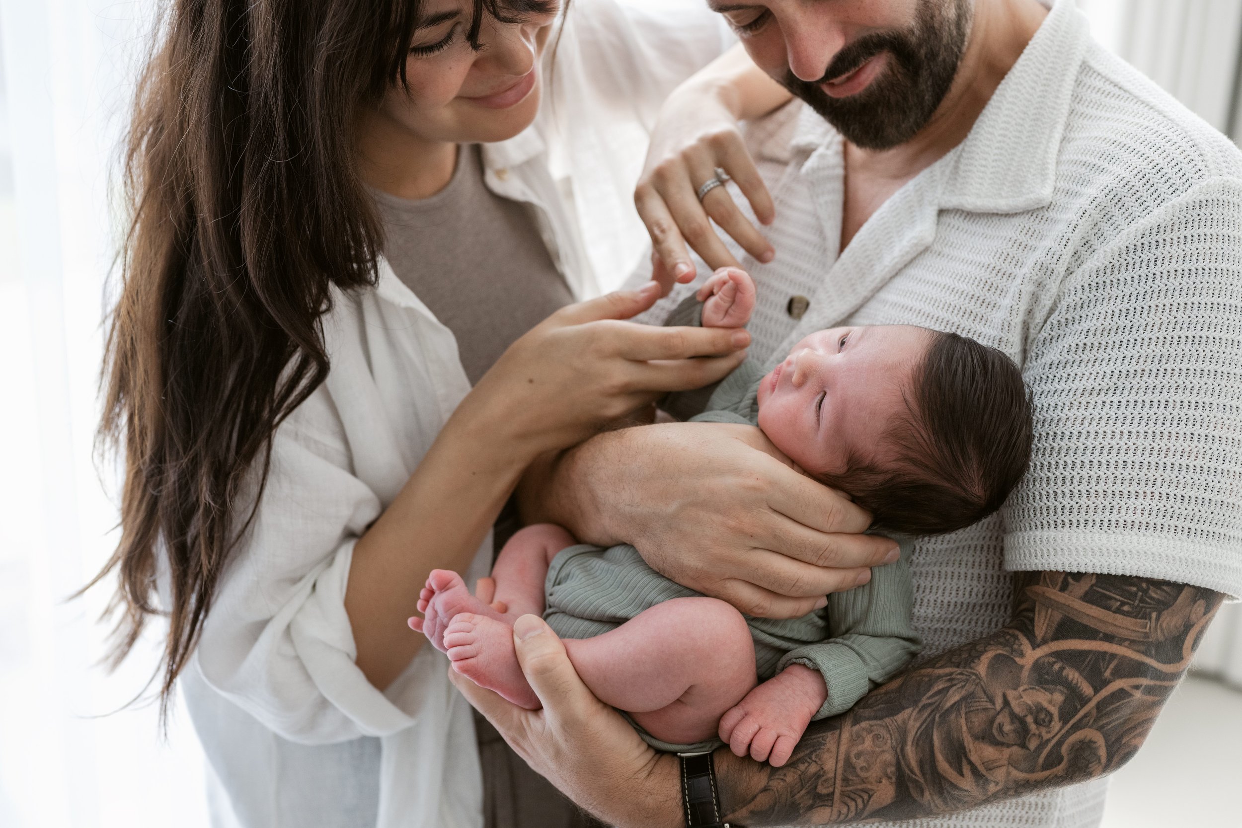 Mother and father cuddling their newborn during an in-home newborn photography session in Dubai