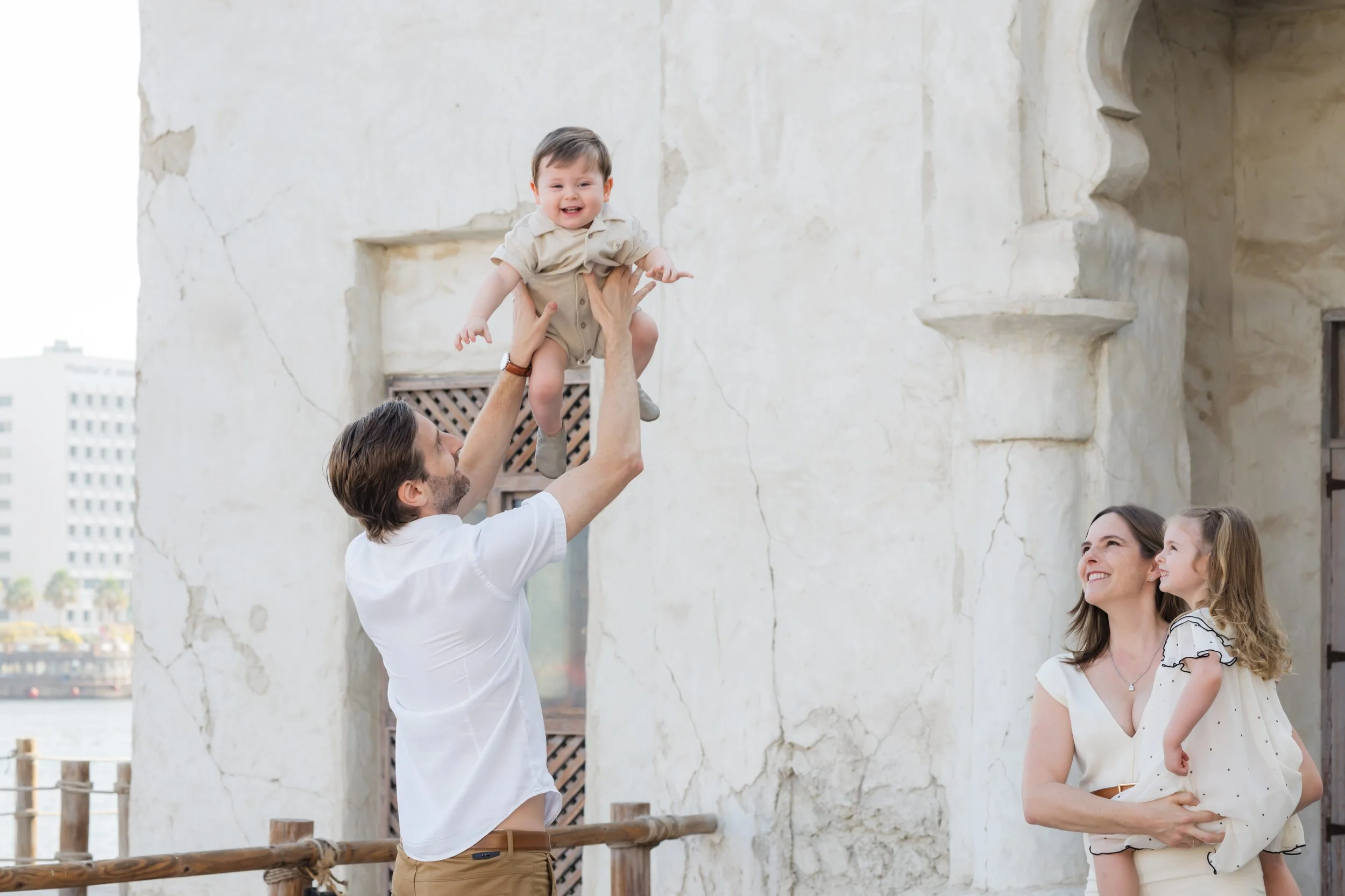 Father lifting baby in the air during a natural family photo session in Old Dubai