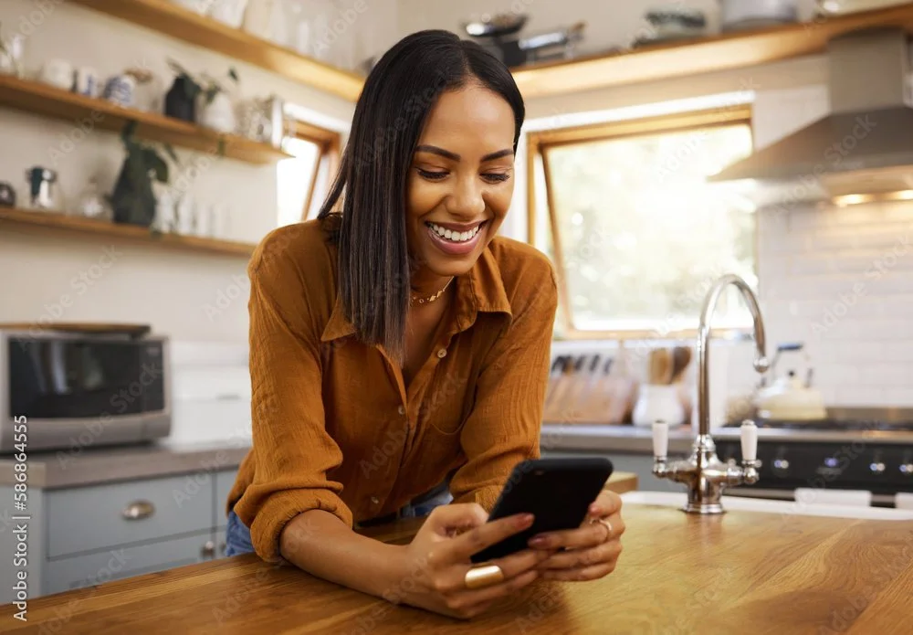 Smiling woman using smartphone in a modern kitchen