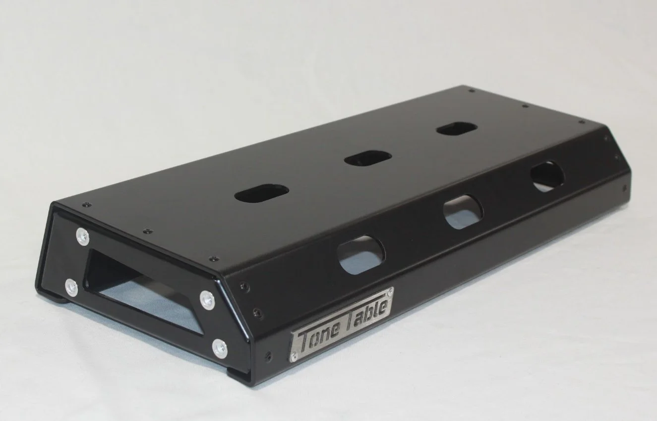 A black sine tone pedal with a metal label reading "Tone Anchor" and six screws on the top surface, used for music production.