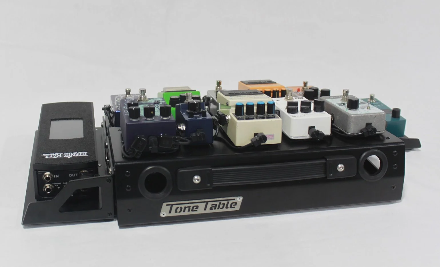A black pedalboard labeled 'Tone Table' with various colored guitar effects pedals mounted on top.