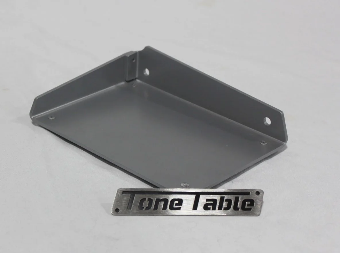A gray metal shelf bracket with a rectangular sticker that says "One Table" in black text.