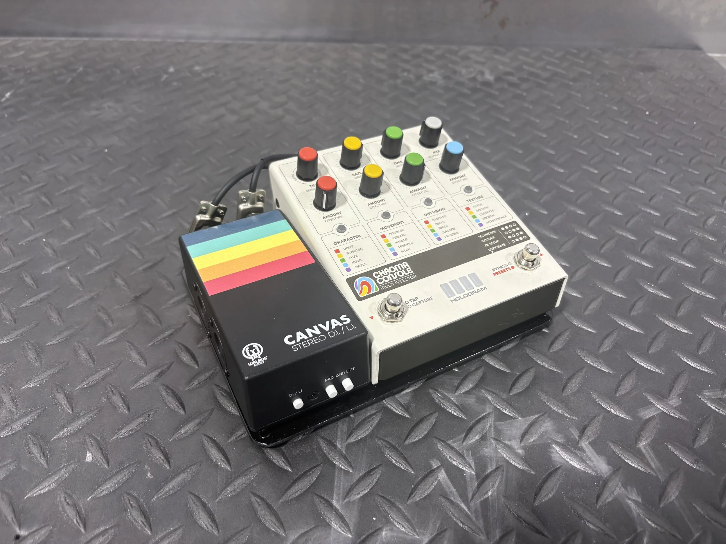 A multi-effects guitar pedal with colorful controls and a smaller pedal labeled Banana Canvas connected to it, placed on a black diamond-patterned surface.