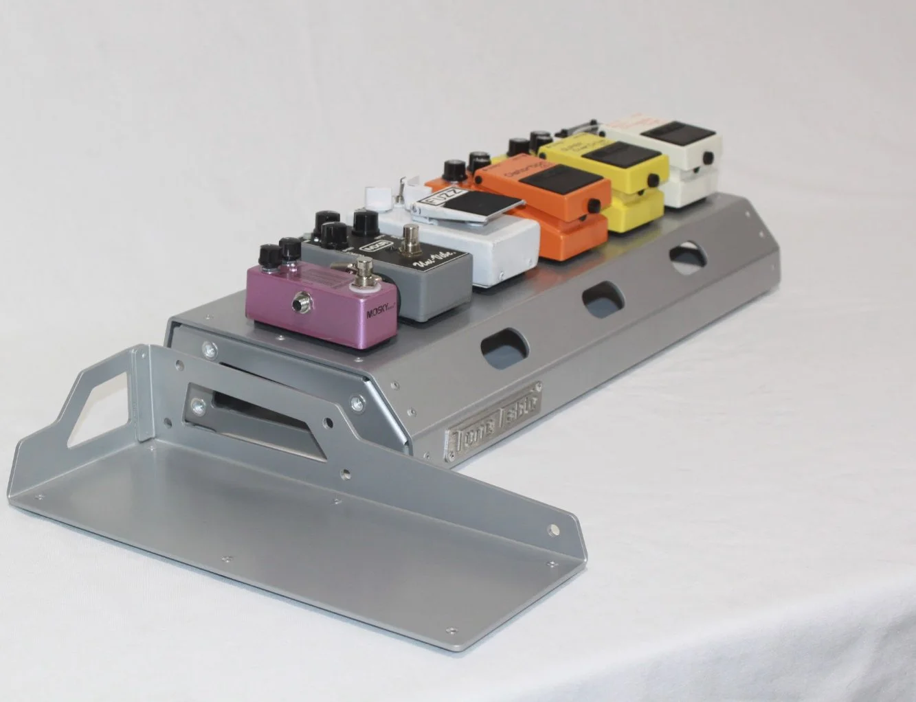Array of colorful guitar effect pedals mounted on a metal pedalboard.