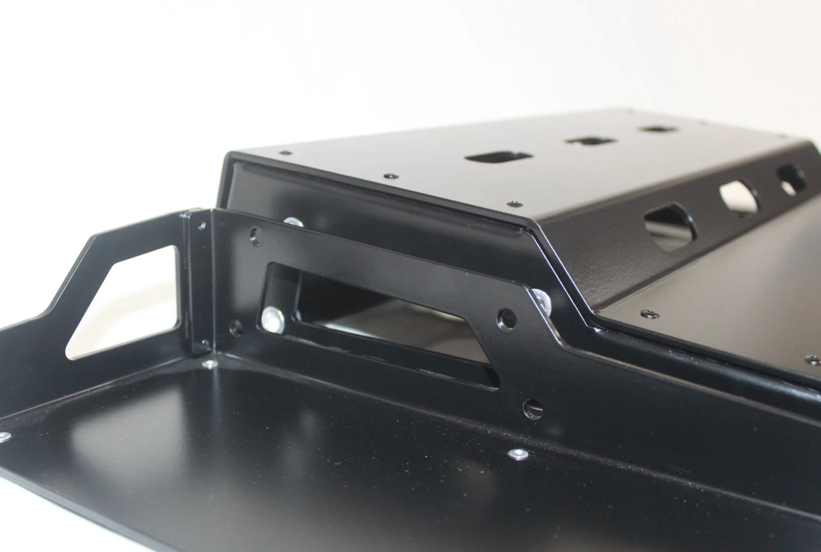 Close-up of a black computer or electronic device enclosure with a handle and multiple screw holes.