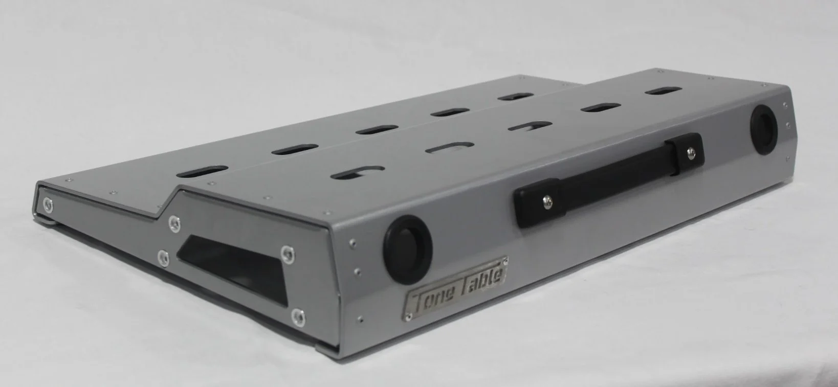 A metal cajón with a handle on one side and black circular features on each corner.