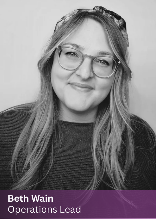 Beth, Operations Lead at The Path, smiling with glasses and long wavy hair in a relaxed portrait.