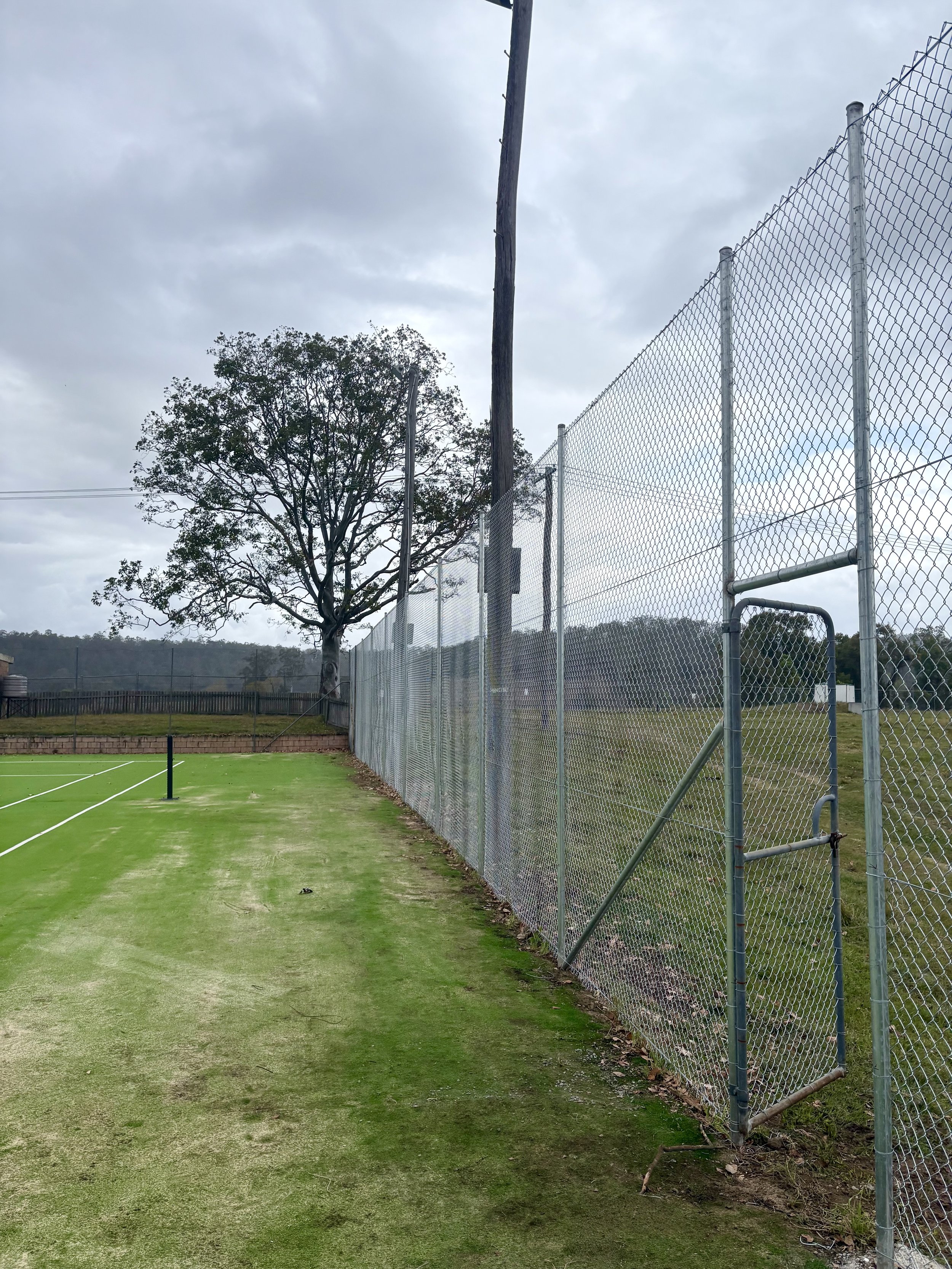 Tennis court fence with pedestrian gate installed by TG Wheeler Contracting
