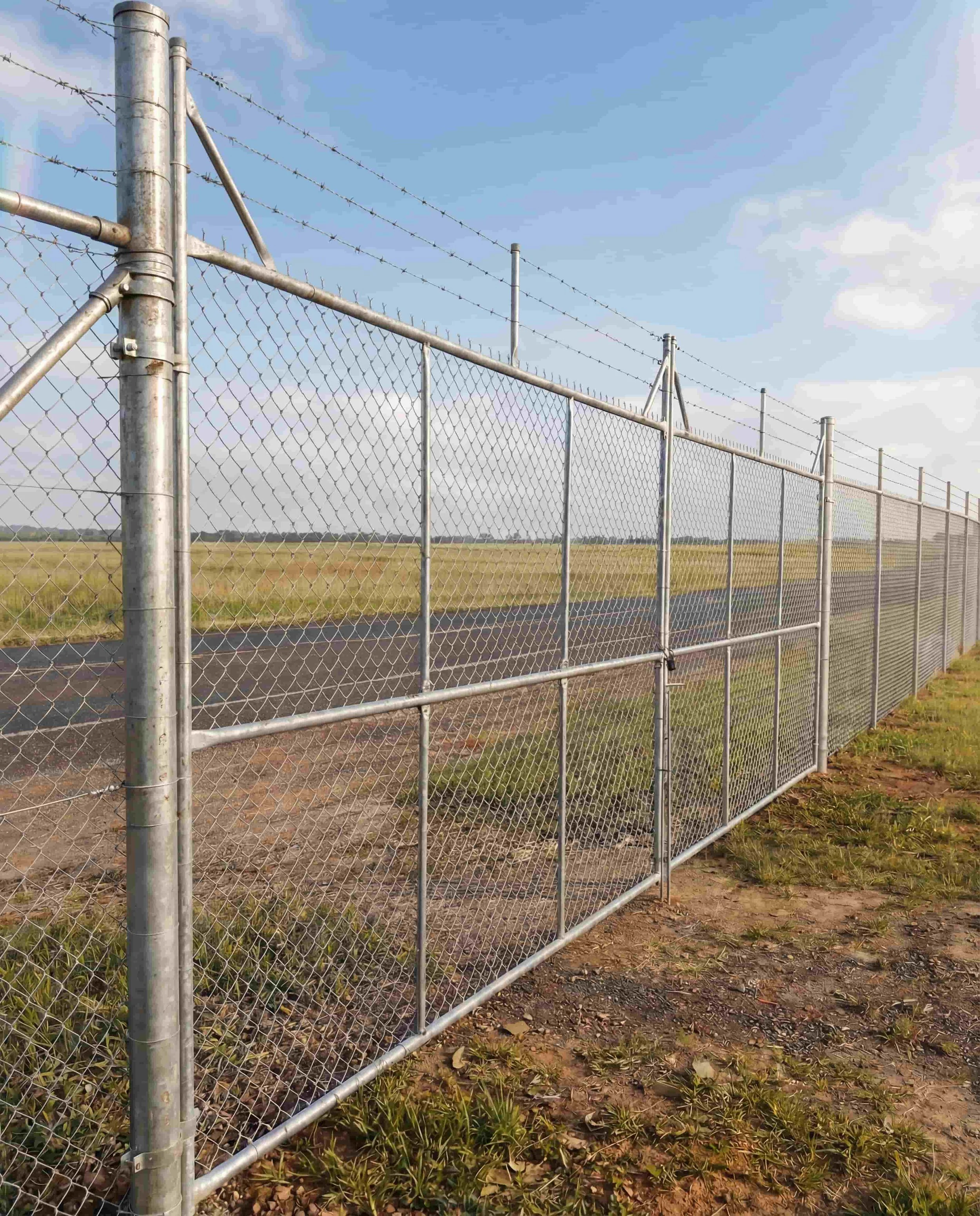 Galvanised chainwire fencing with barbed wire topping and double swing gate along rural perimeter, Northern Rivers NSW