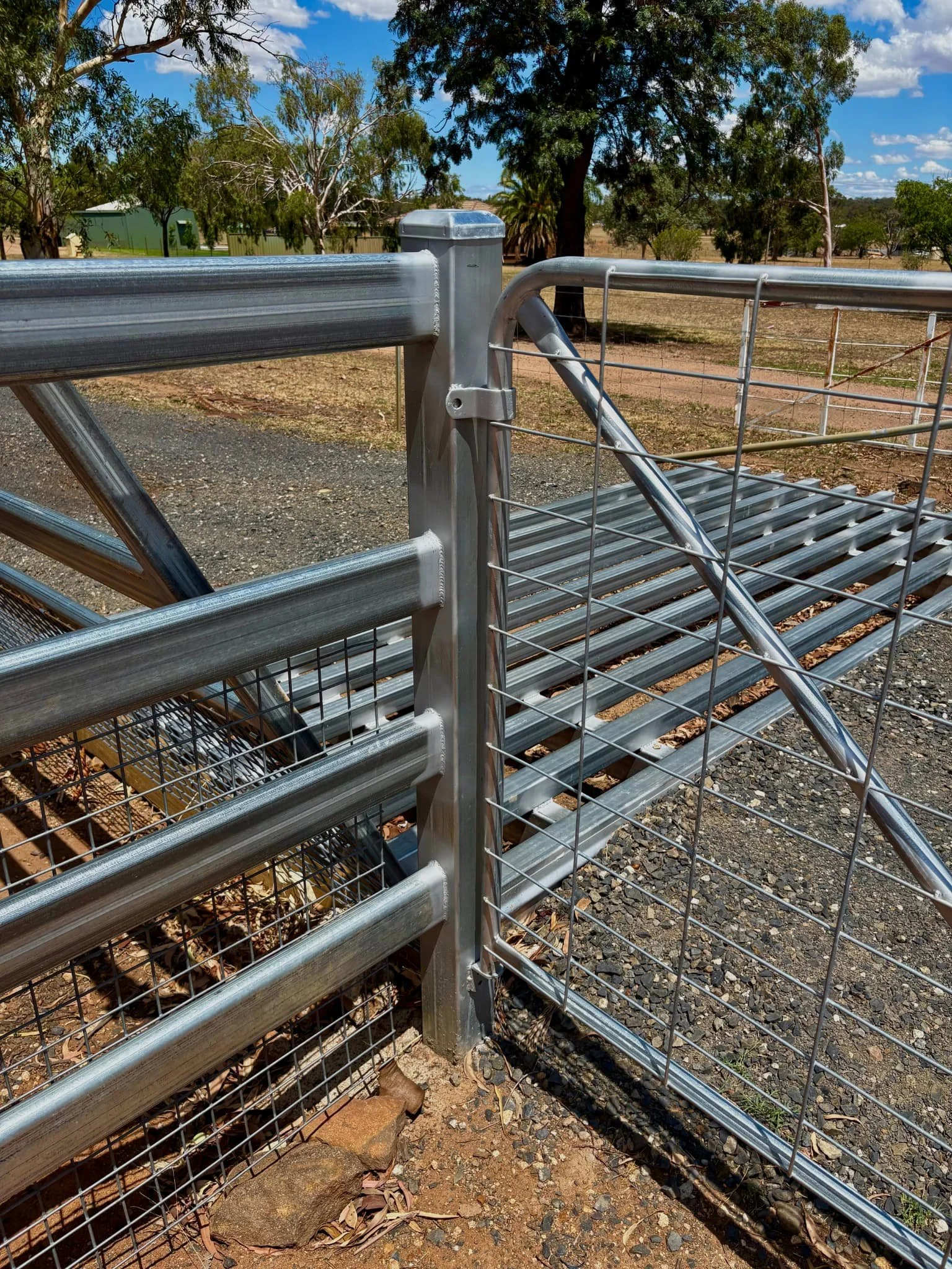 Close-up of galvanised gate hinge on post beside cattle grid, rural farm gate installation NSW