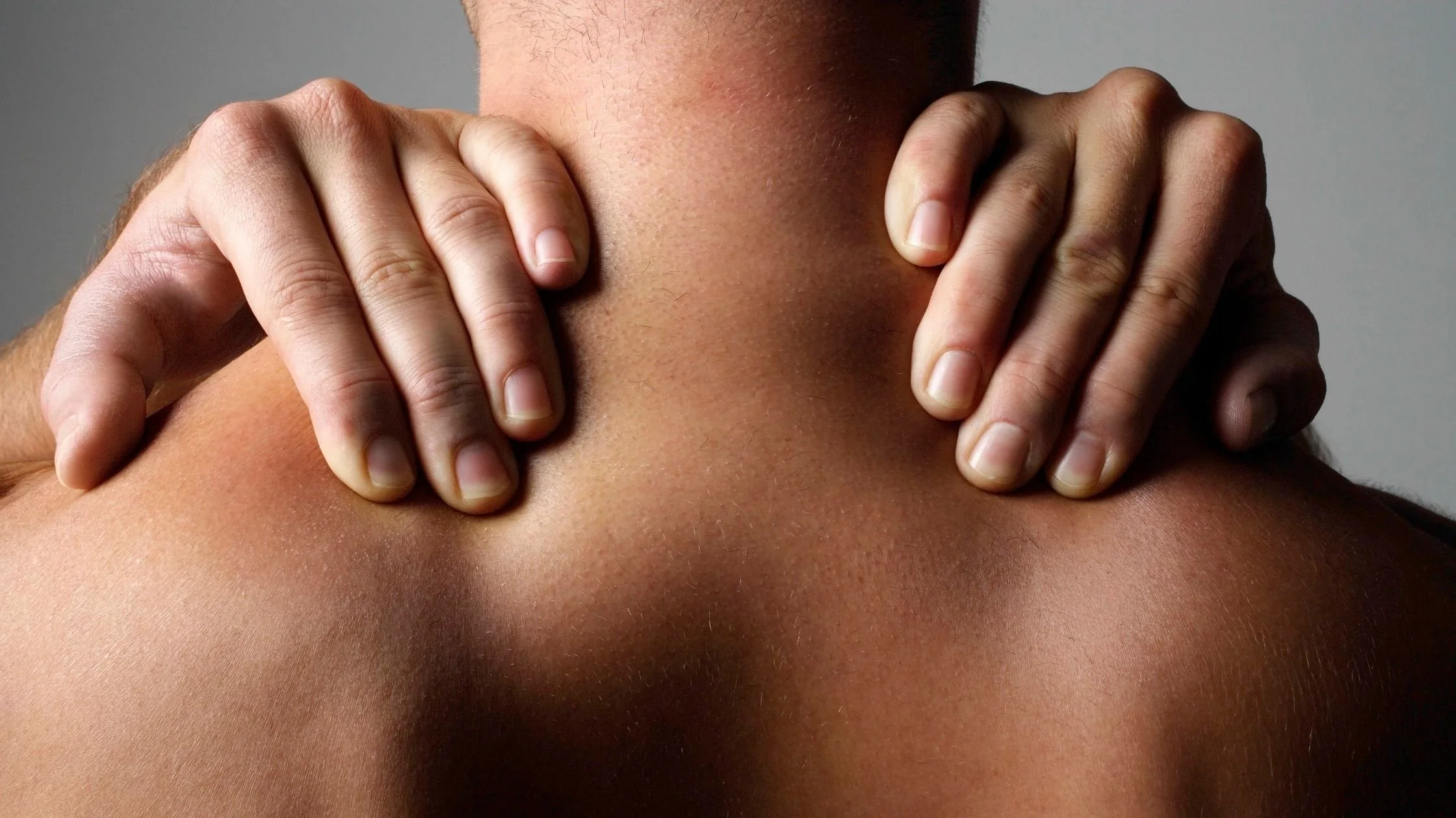 Hands massaging the base of the neck