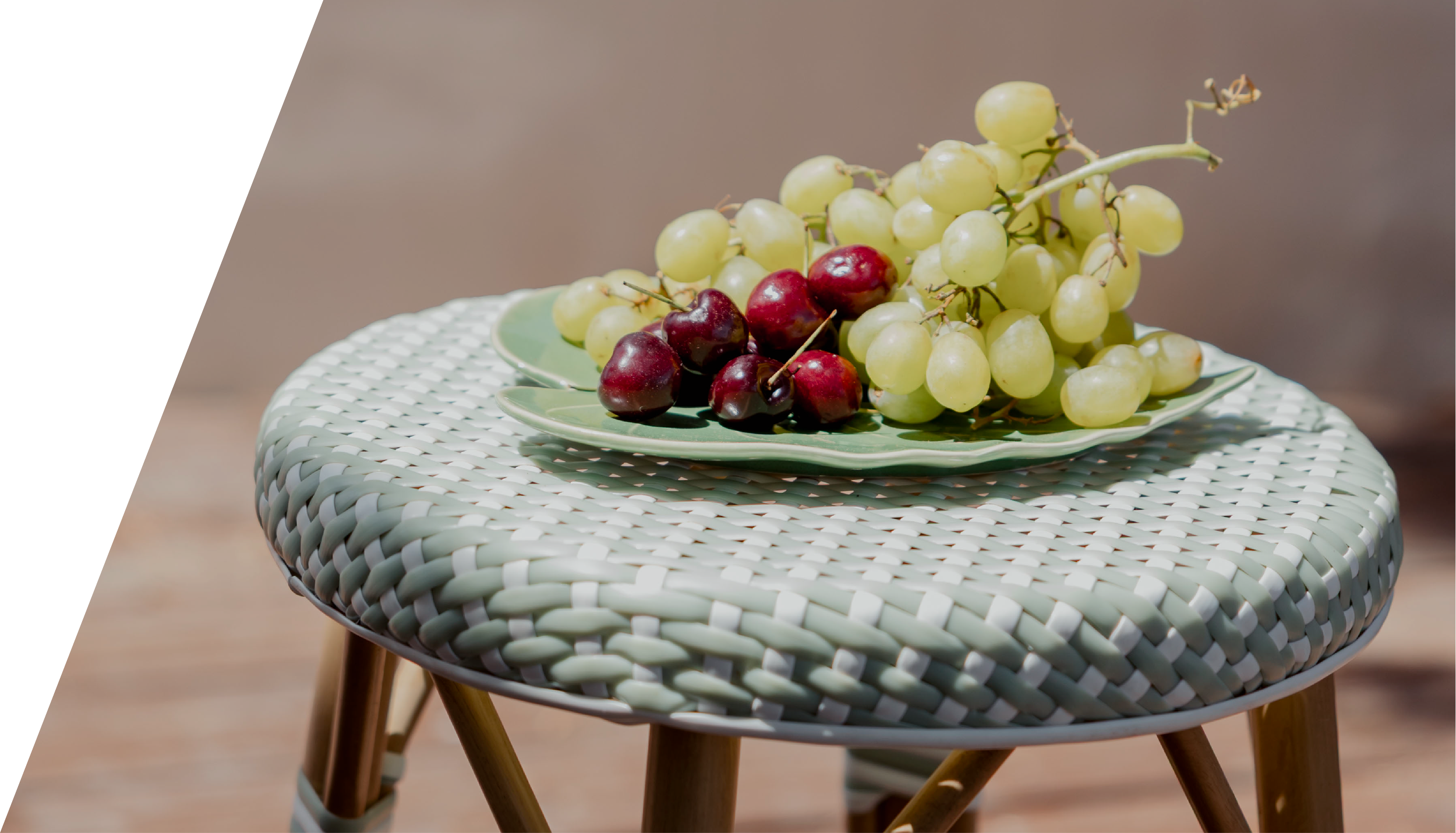 Uvas verdes y negras en un plato sobre una mesa de ratán con pedestal de madera