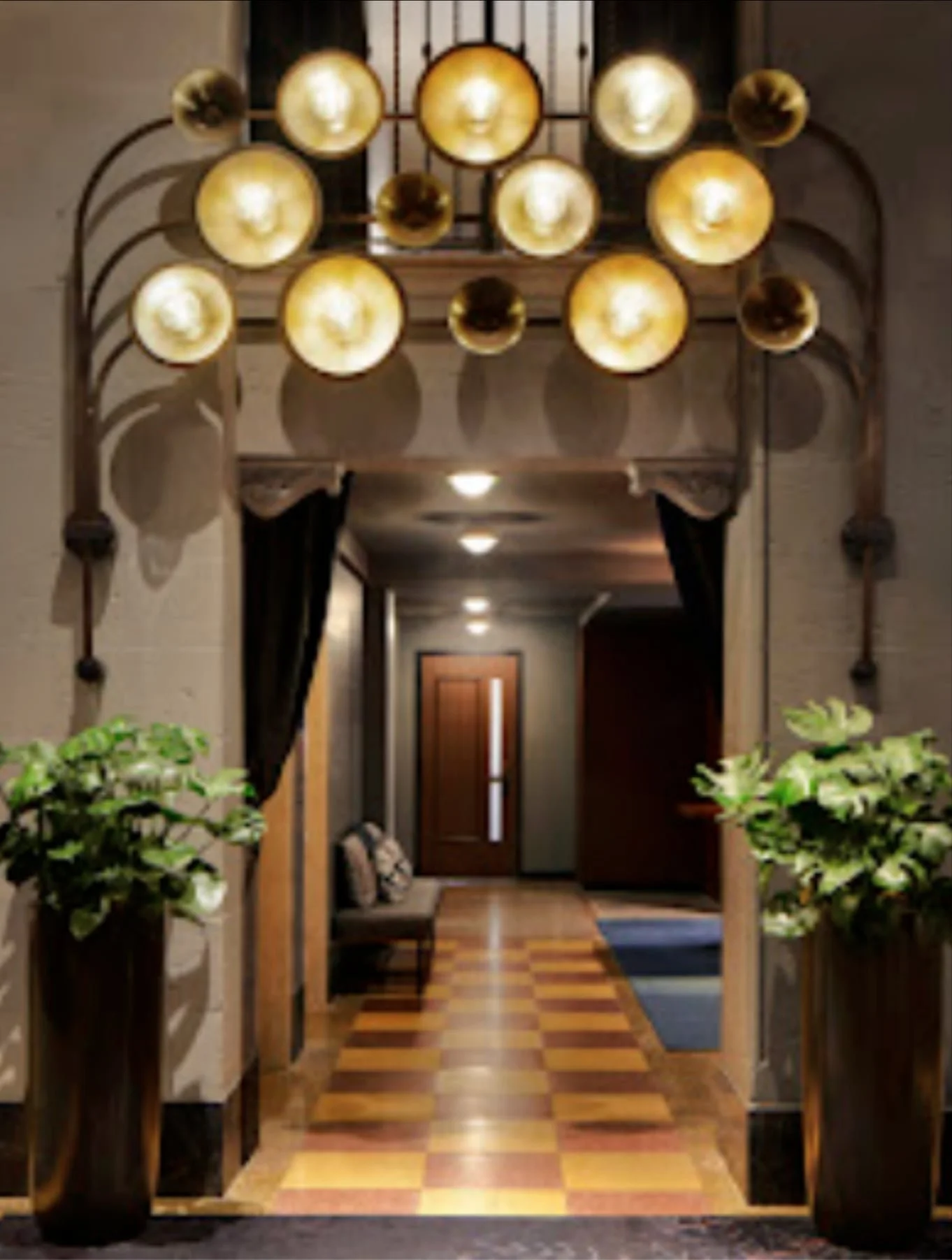 Modern hallway with golden circular lights, checkered floor, and tall potted plants flanking a curtained entryway.