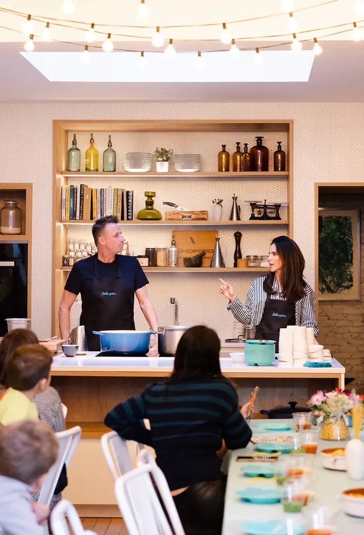 A cooking class with a man and a woman in front of a group of people