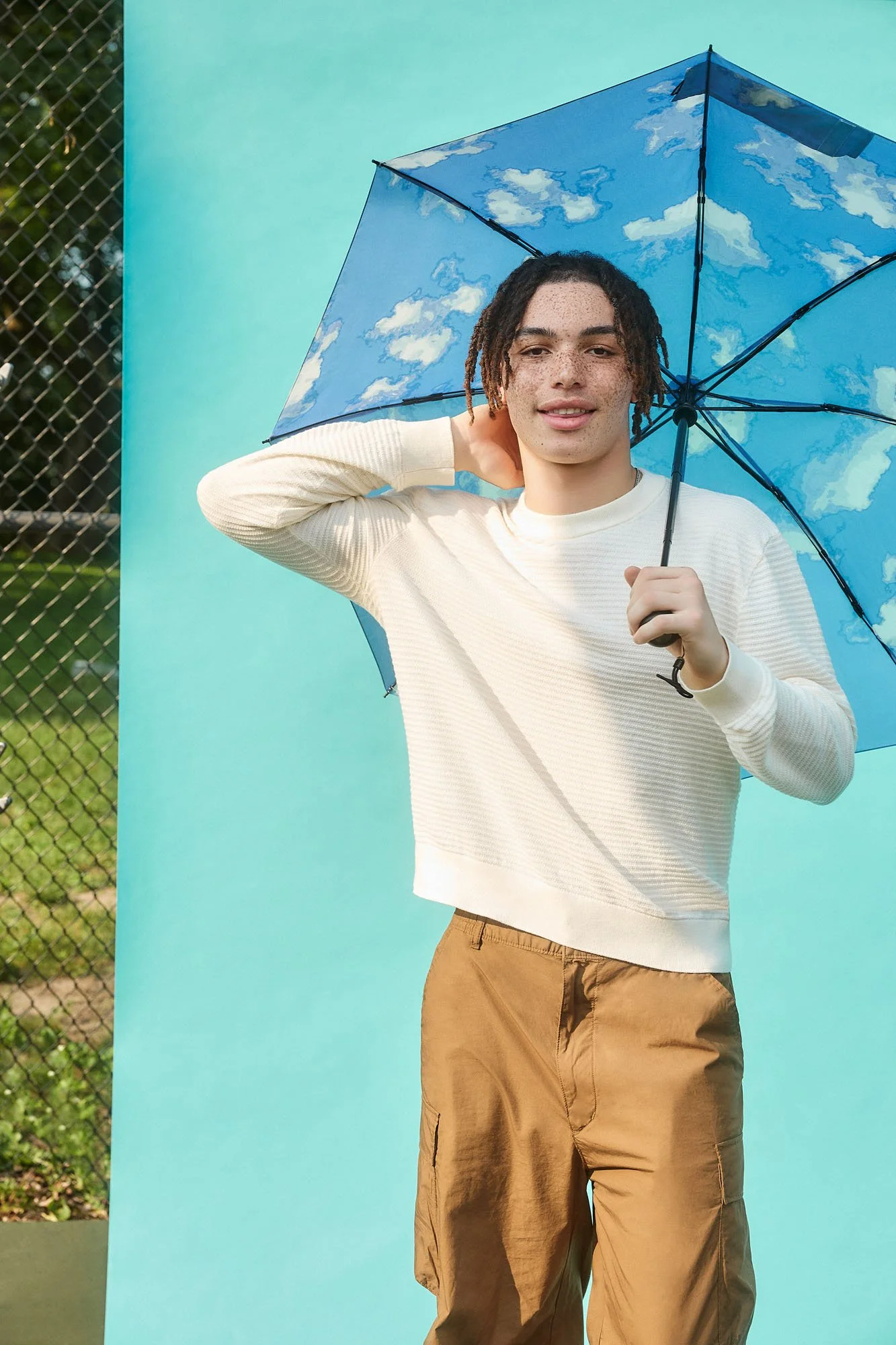 young man holding umbrella with blue background