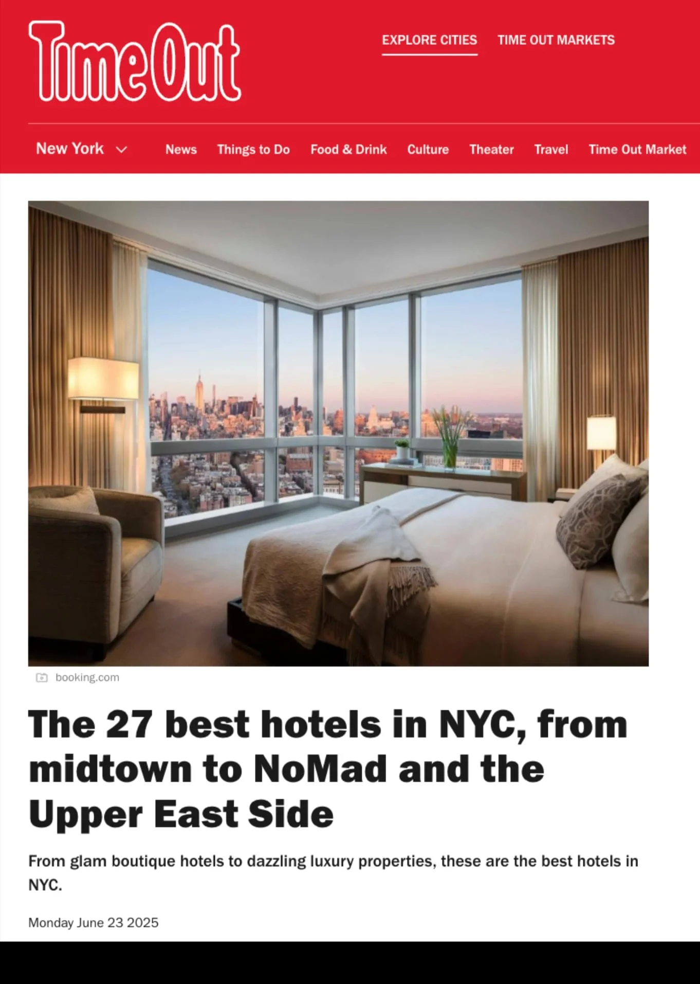 A modern hotel room with large windows offering a panoramic view of the New York City skyline at sunset.