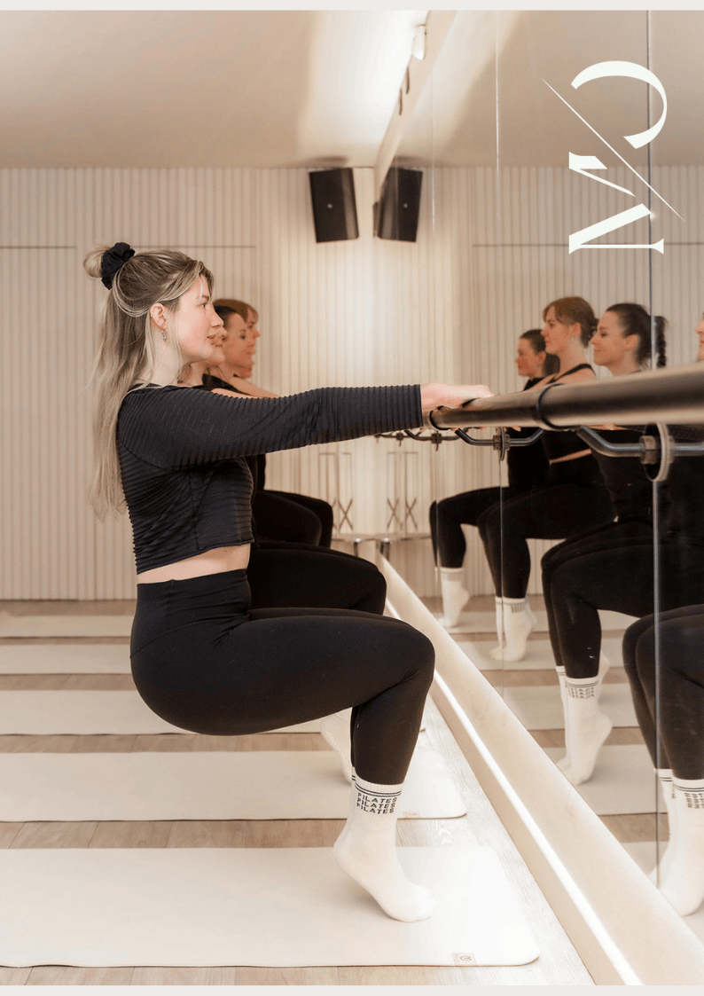 Woman in black doing barre fitness class in a studio