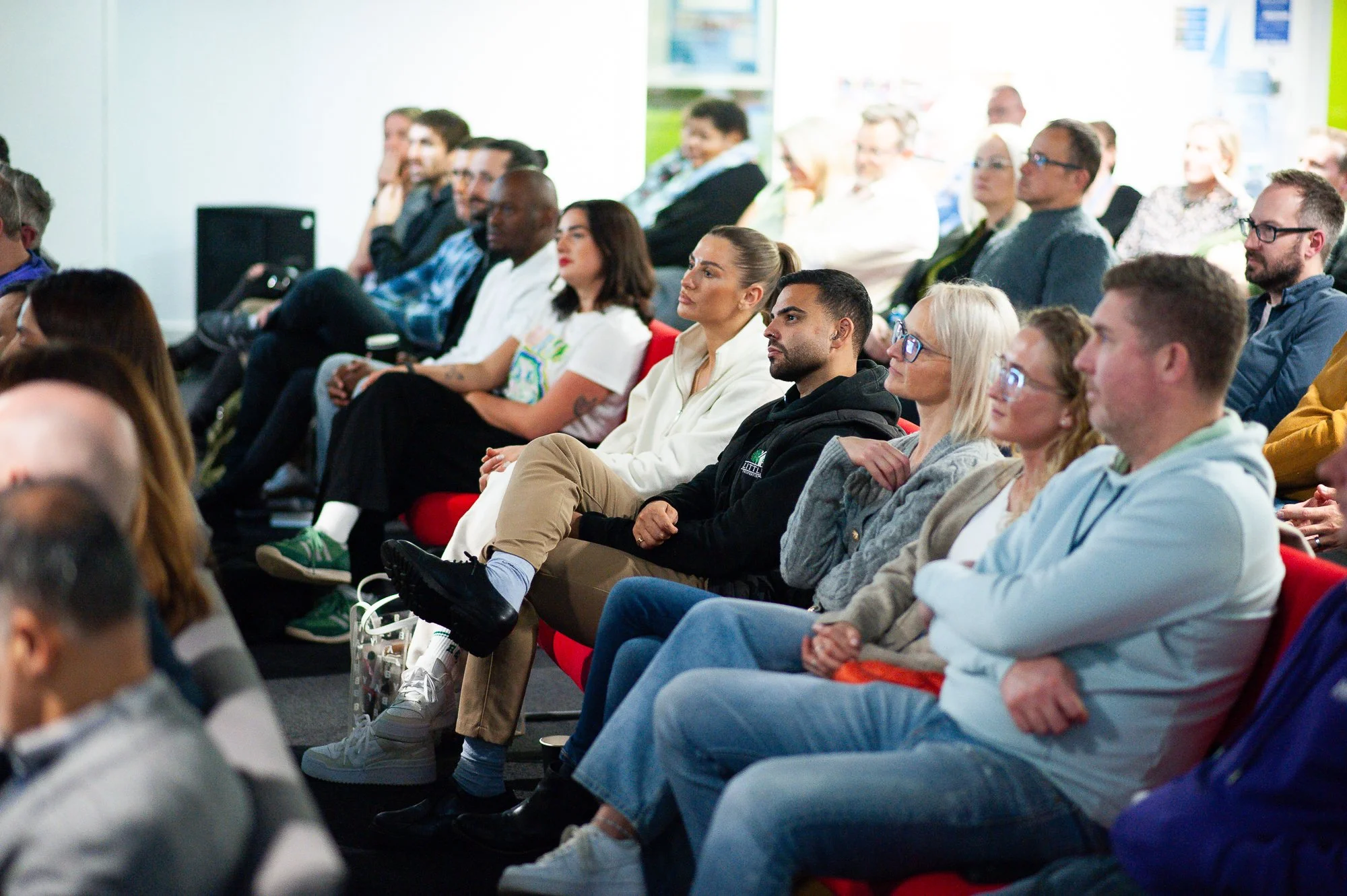 Audience attending a conference or seminar, sitting in rows of chairs and listening to the speaker.