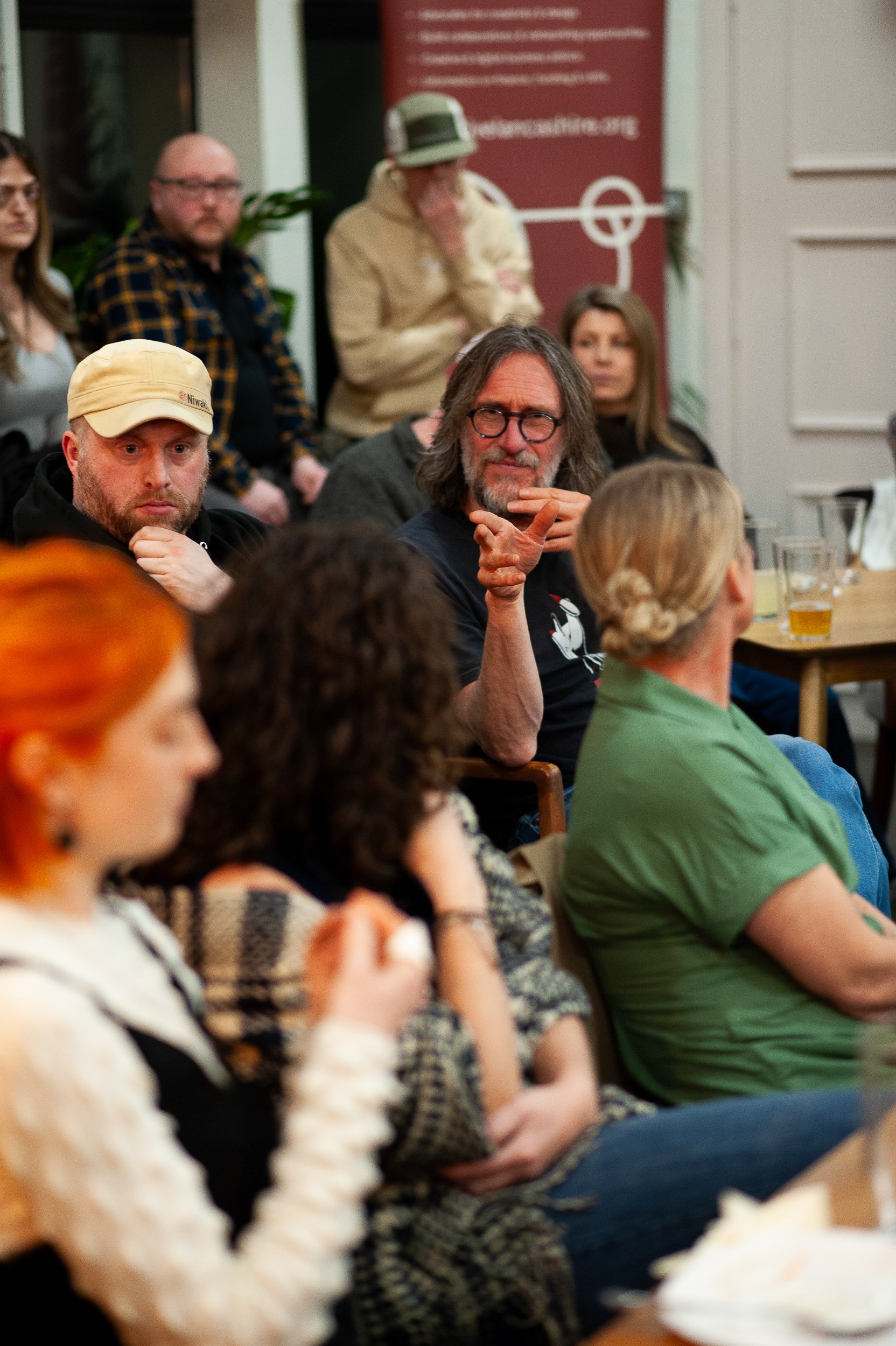 Group of people seated, engaging in conversation at an indoor event.