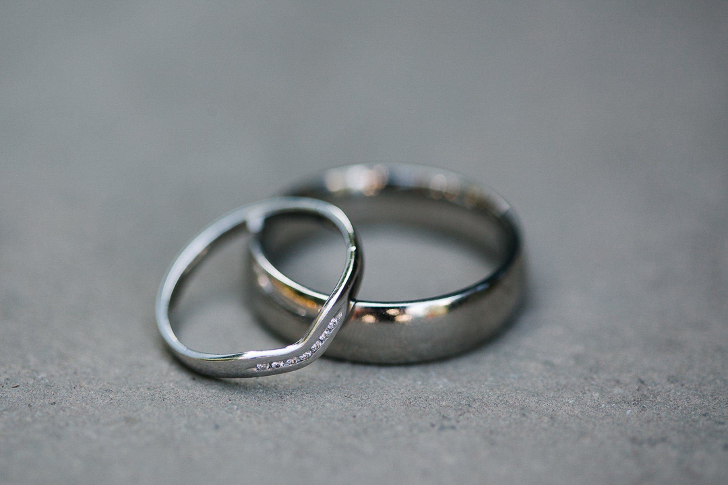 Two silver rings on a gray surface, one plain and one with small embedded stones.