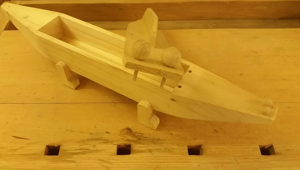 Unvollendetes Holzmodell eines Bootes auf einem Holztisch.