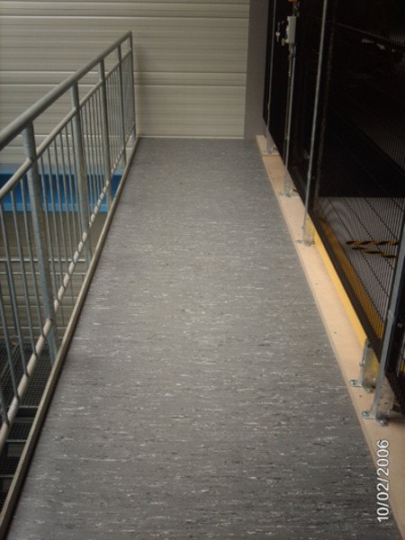 Ein schmaler Gang in einem Serverraum mit Metallgeländer auf der linken Seite und Server-Racks auf der rechten Seite.