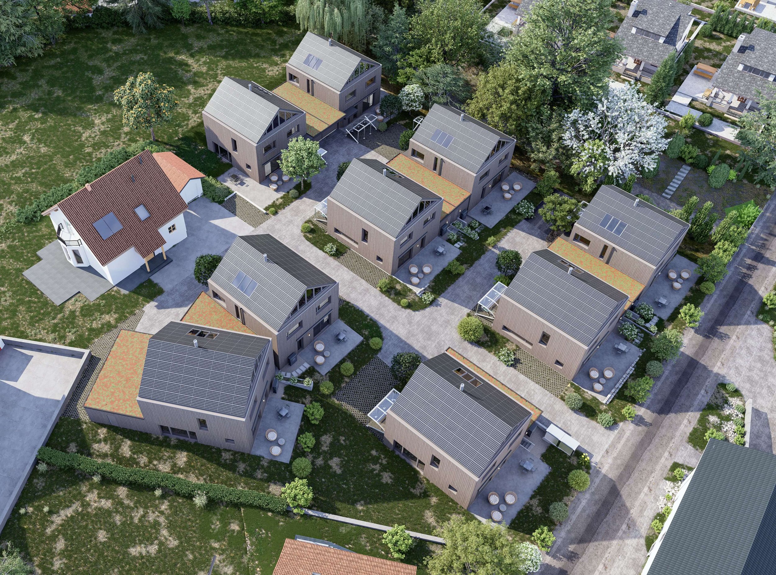 Luftaufnahme eines Wohnviertels mit mehreren modernen Häusern, bewaldetem Hintergrund und einer breiten Straße