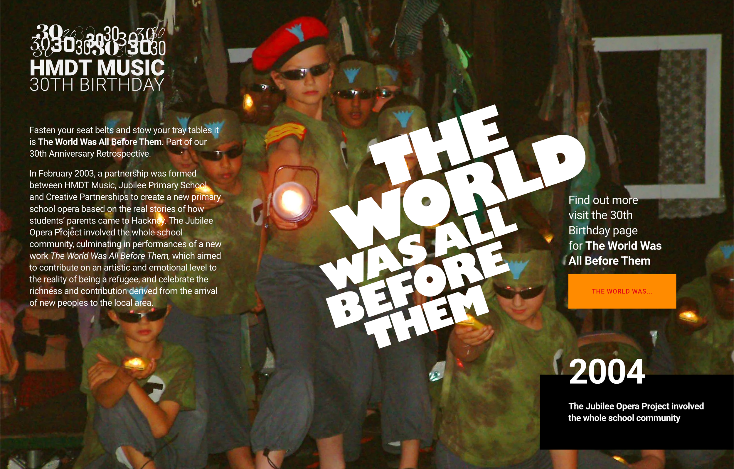 Children dressed in camouflage shirts, some wearing sunglasses and hats, holding flashlights, on a stage with a dark background, celebrating the 30th birthday of HMDT Music with a large overlay text reading 'The World Was All Before Them.'