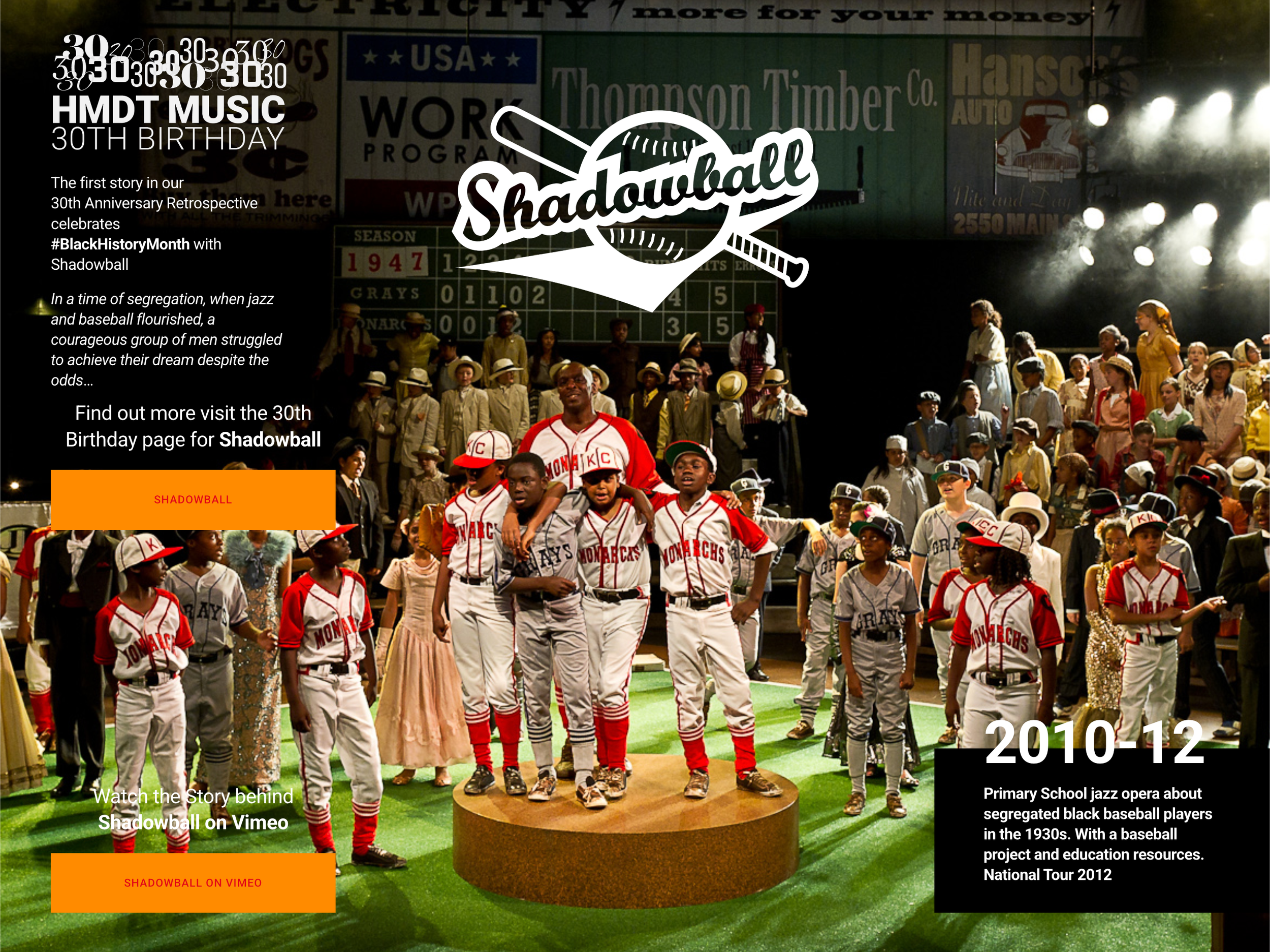 Children dressed as baseball players and performers on stage, with audience and stage backdrop, and a large Shadowball logo in the center, celebrating the 30th birthday of Shadowball for Black History Month.