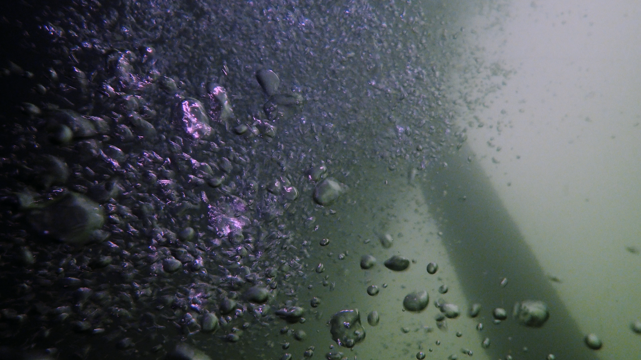 Underwater bubbles rising with a greenish tint.