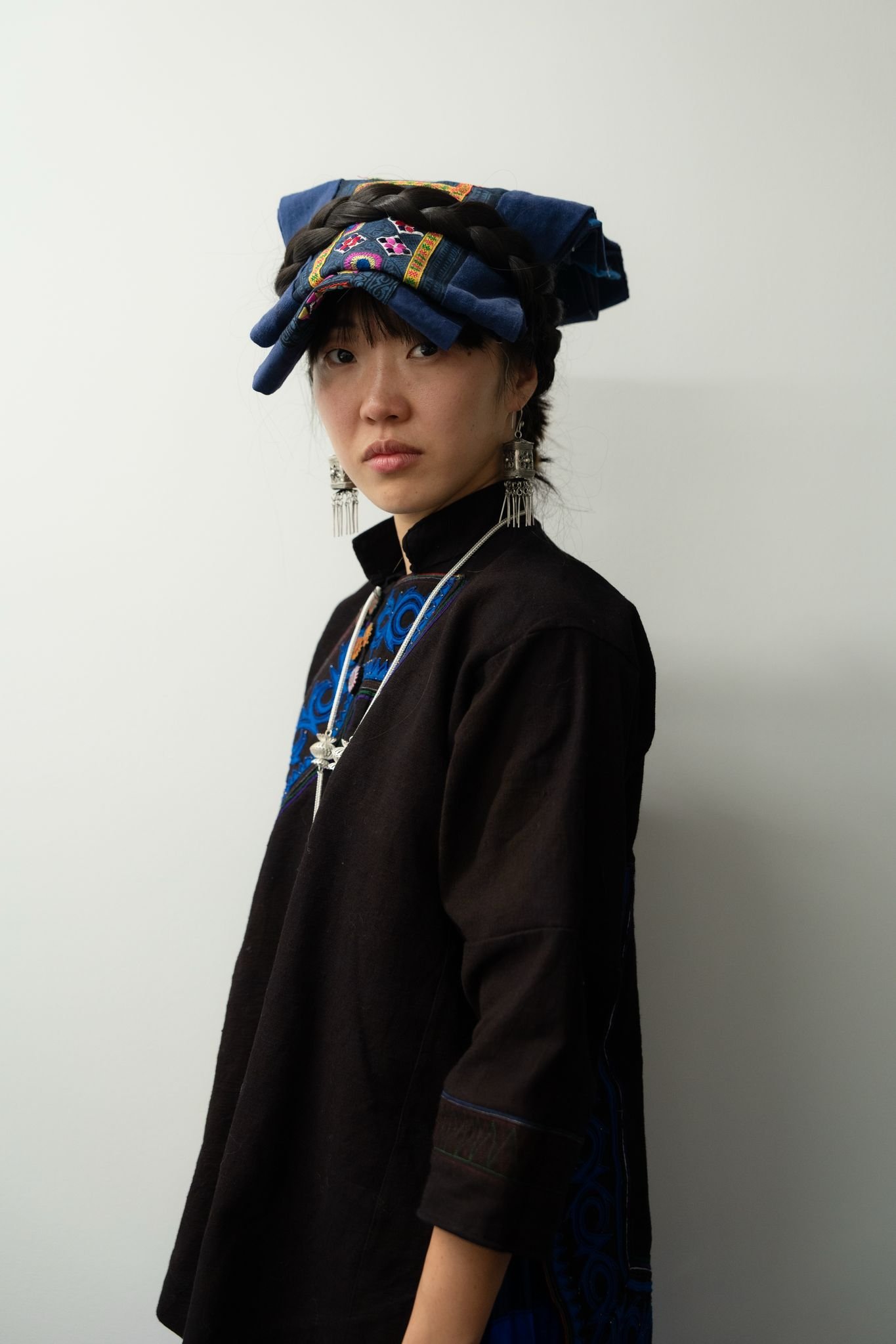Person wearing traditional Asian clothing with a detailed headdress and large, ornate earrings.