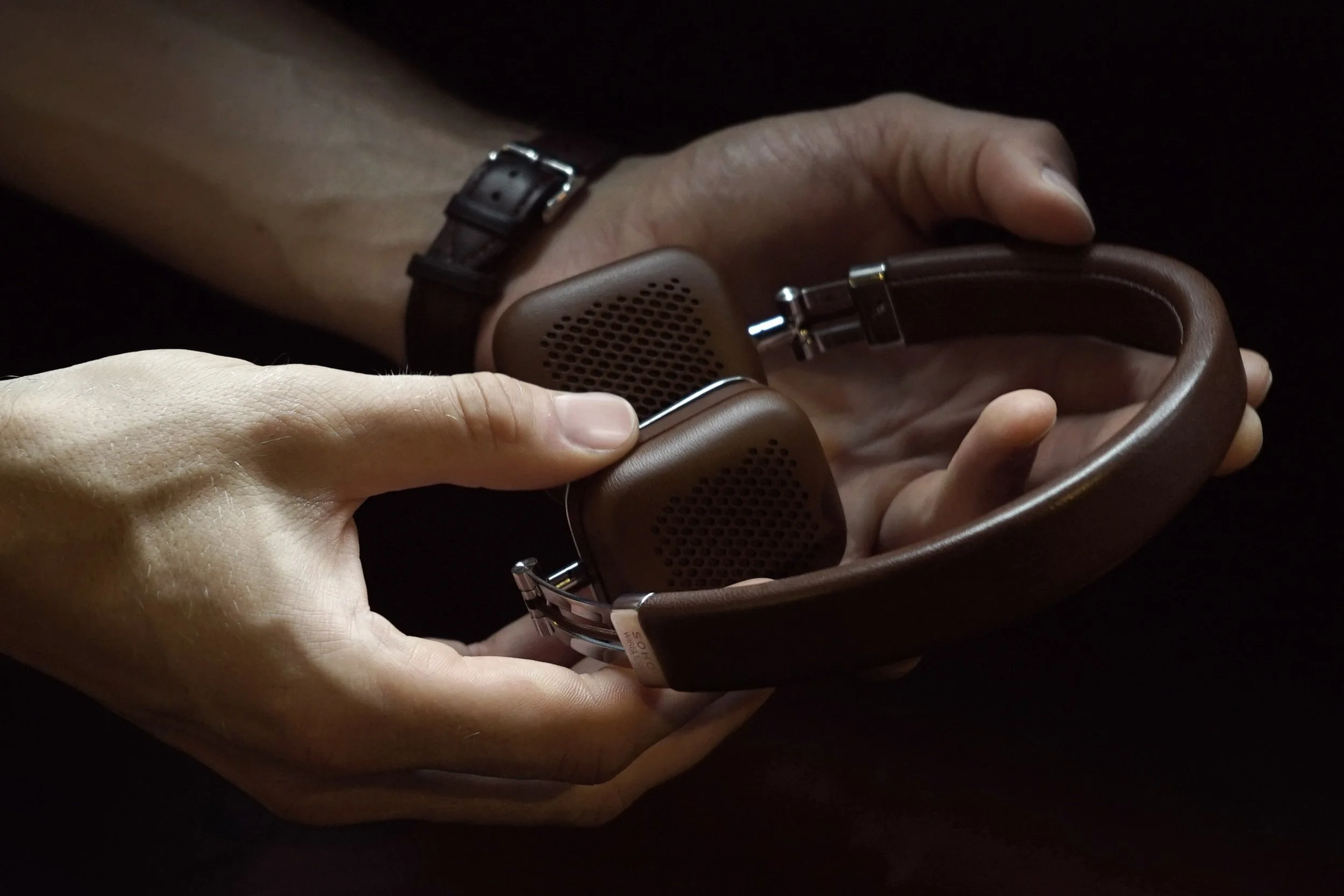 Close-up of hands holding folded Harman Kardon Soho Wireless headphones