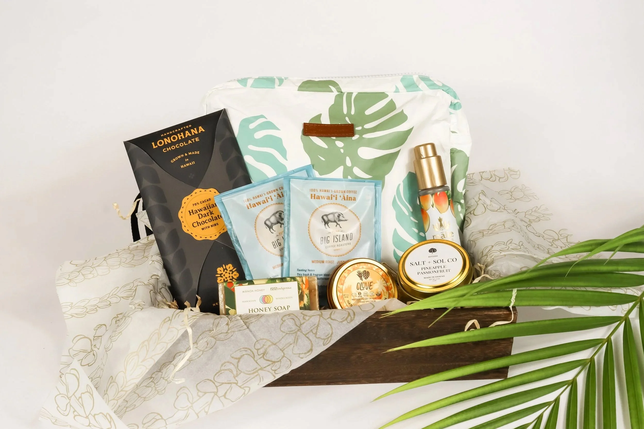 Welcome gift for a Hawaiian hotel, featuring a waterproof pouch, local coffee and chocolate, reef-safe sunscreen, small luxury candle, and local skincare products