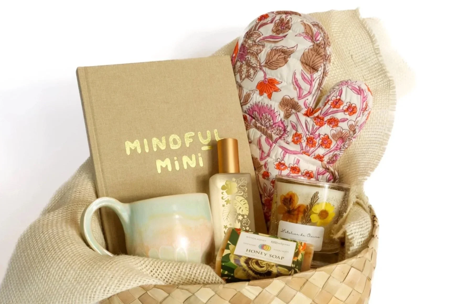 Hawaii housewarming gift featuring a handmade mug, mindfulness journal, floral printed oven mitt, luxury candle with embedded flowers, room spray, and Hawaiian honey soap