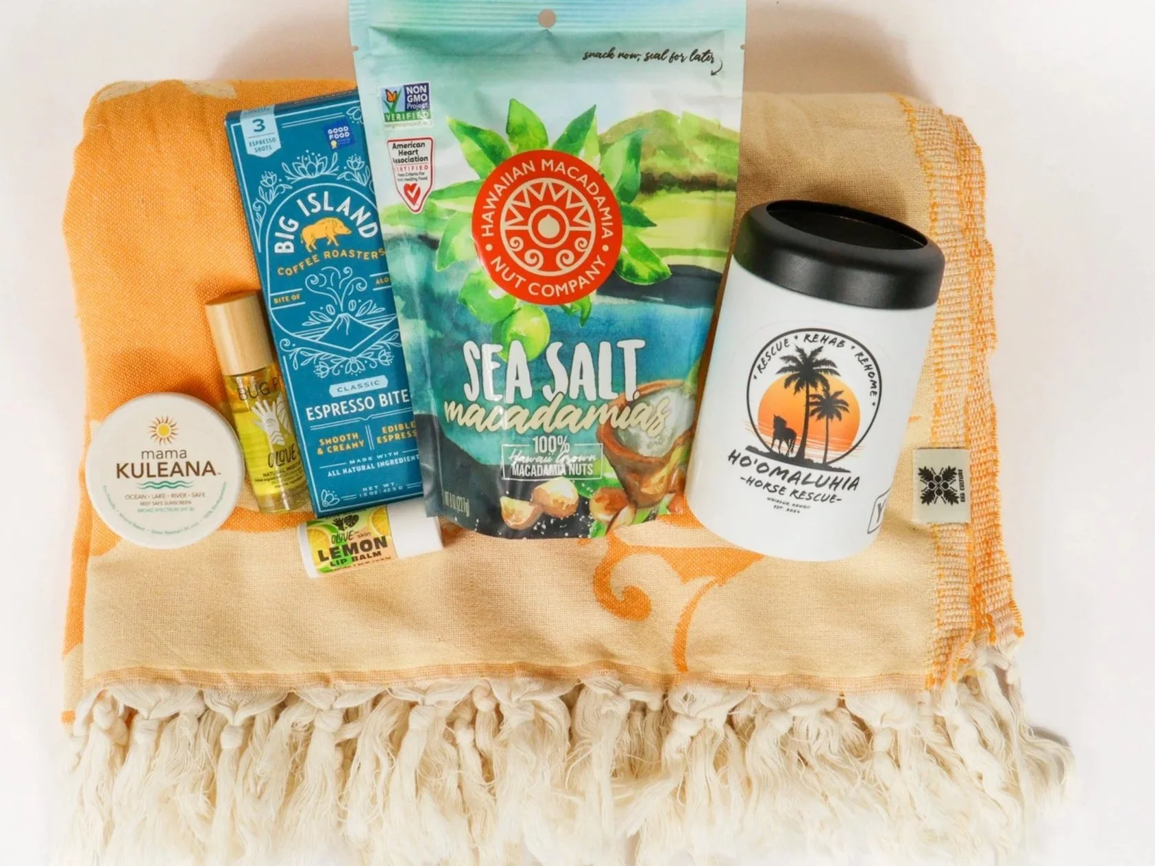 Hawaii travel gift featuring a pareo, local snacks, reef-safe sunscreen, and other local goods