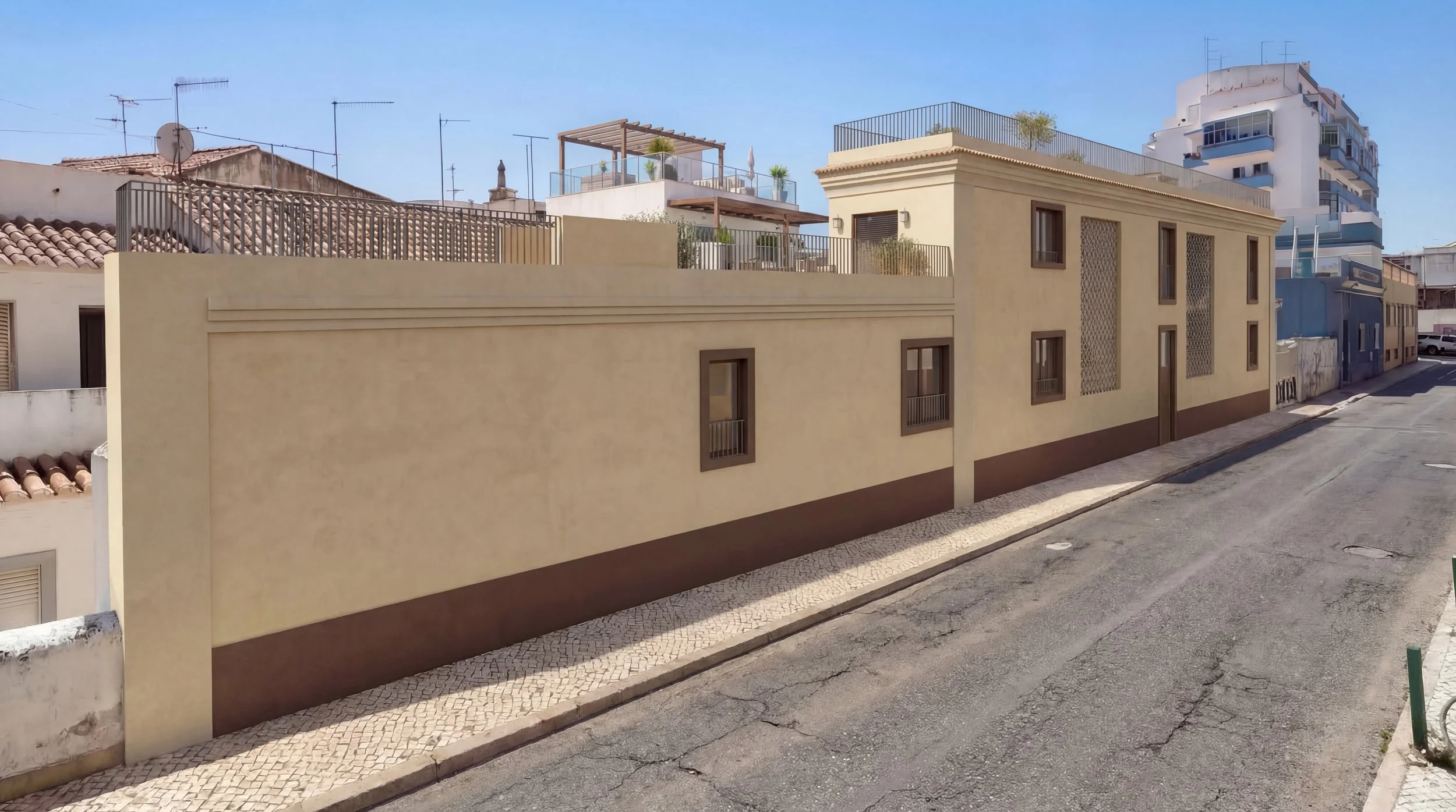 The Triangle Facade in Portimão. A residential street view with a beige building featuring small windows, beautiful balcony and rooftop terrace and a decorative roofline, and a sidewalk with a patterned surface.